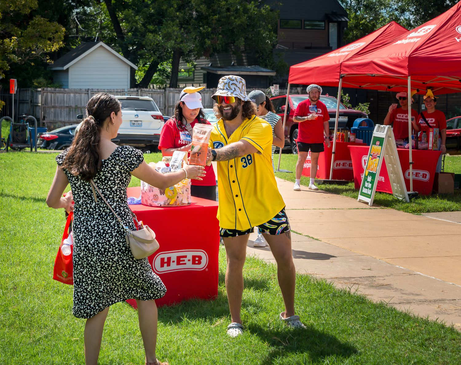 Outdoor event setup with red tents and people gathering on a sunny day.