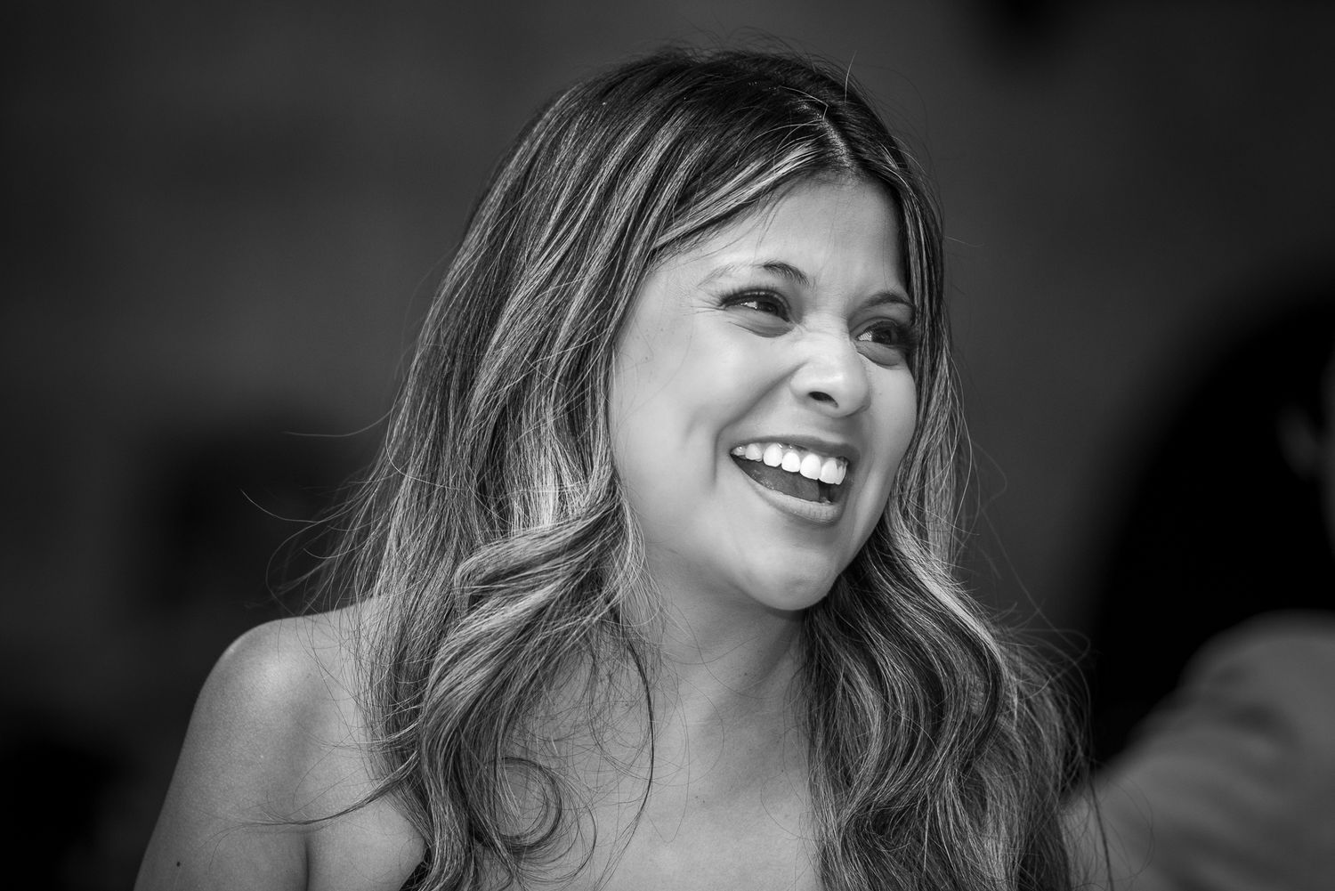 Black and white candid shot of someone laughing at a celebration.