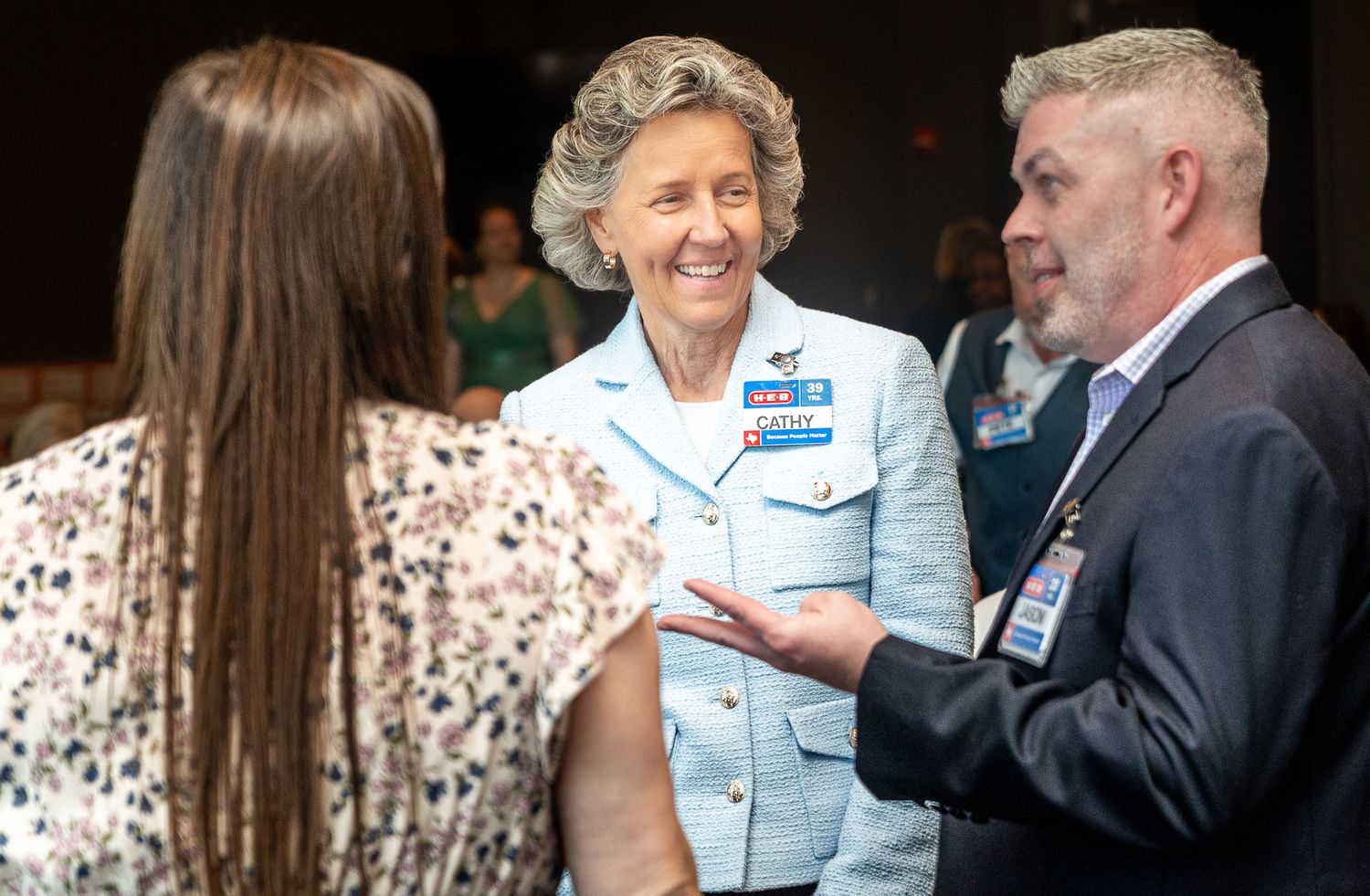 Three people engaged in animated conversation at a professional networking event.