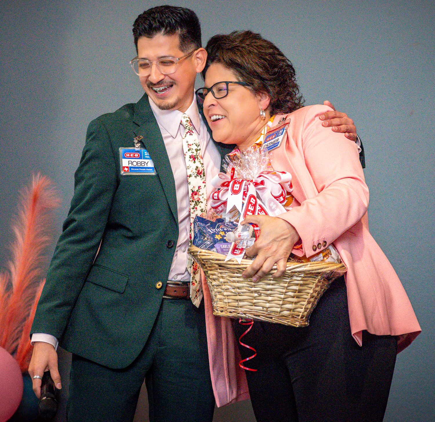 A presentation moment showing someone in pink holding a gift basket on stage.
