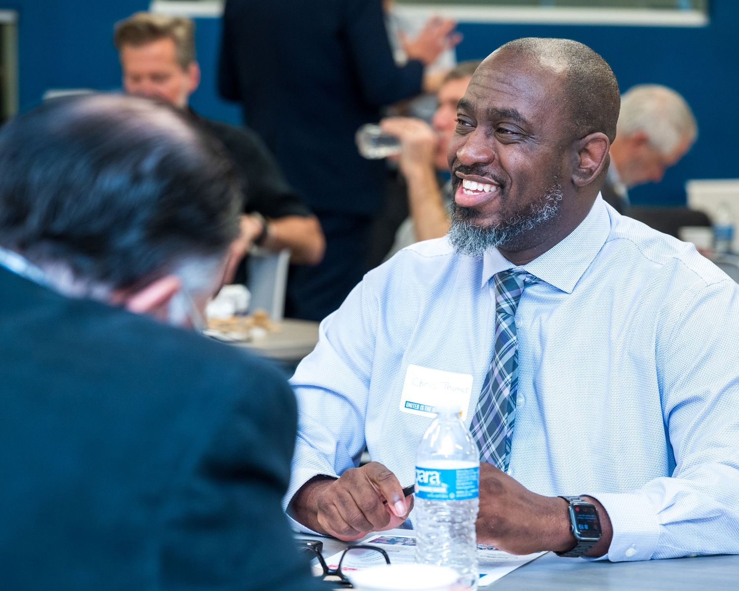 A series of photos showing a person in business attire smiling and engaging in conversation during a professional event.