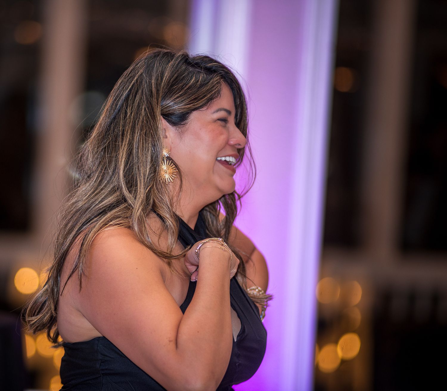 Guests sharing laughs and embraces under purple ambient lighting at an evening event.