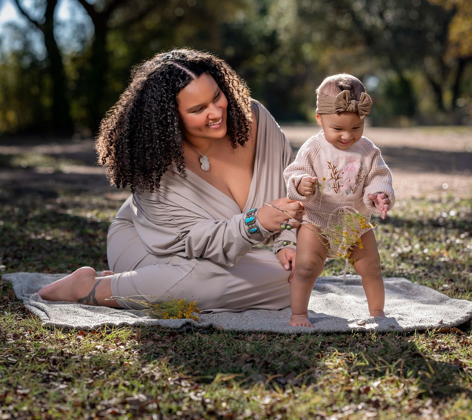 Mother and child lying on a blanket outdoors enjoying a sunny day together.
