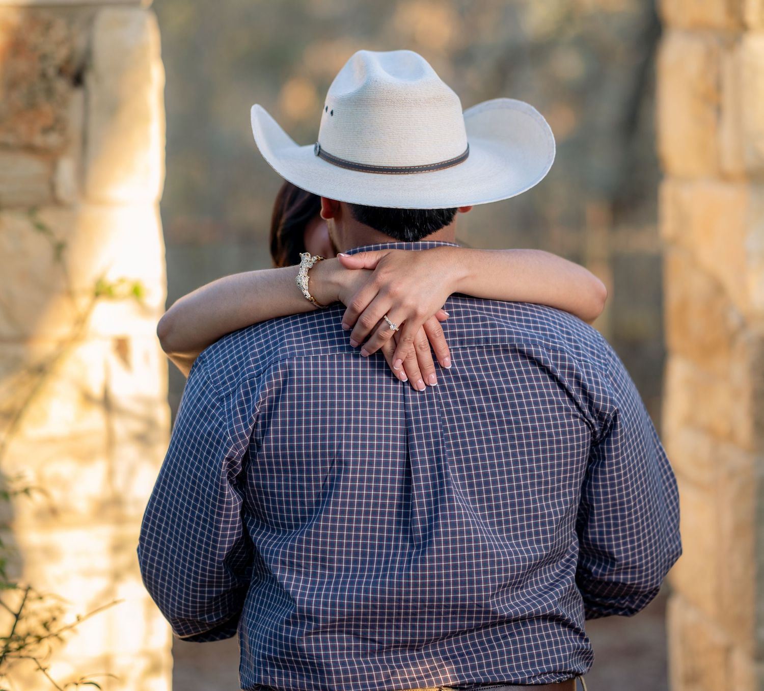 Couple in coordinated outfits embracing outdoors at sunset.