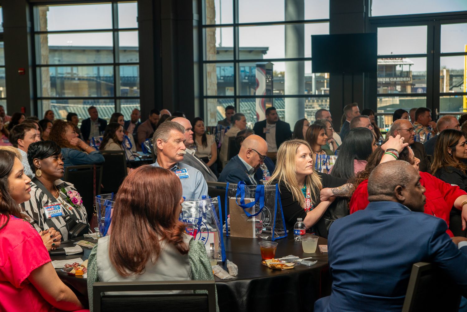 Audience members seated in rows applaud during a formal event in a large conference room.