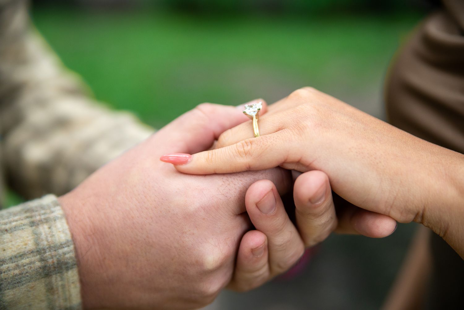 Detailed shot of hands with engagement ring being held tenderly.