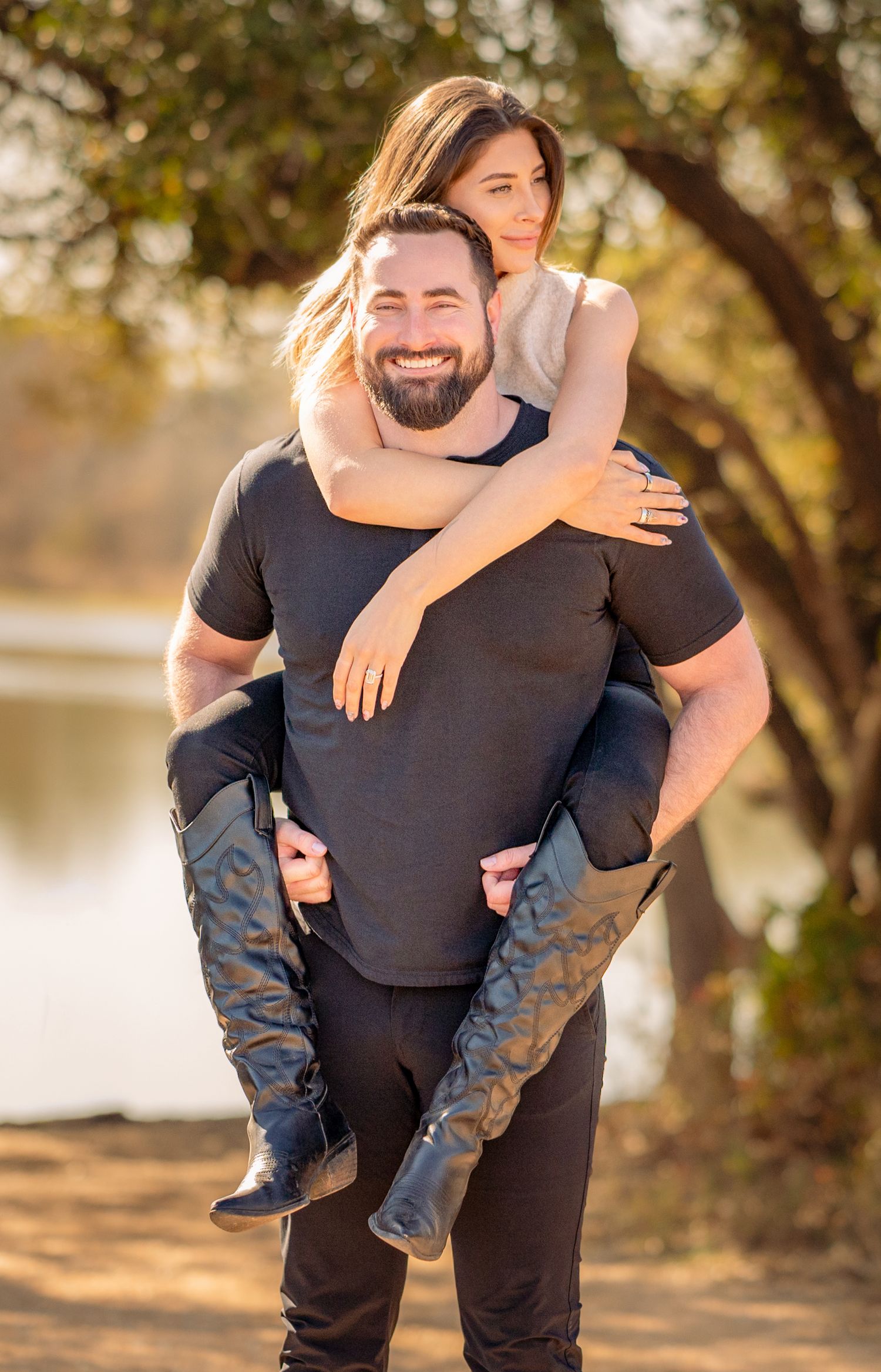 Playful piggyback ride by lake with trees in background.