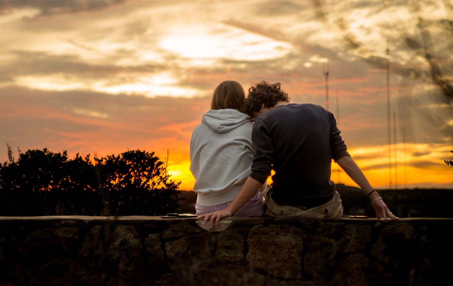 A series of silhouetted sunset scenes showing couples sitting together against dramatic orange and purple skies.