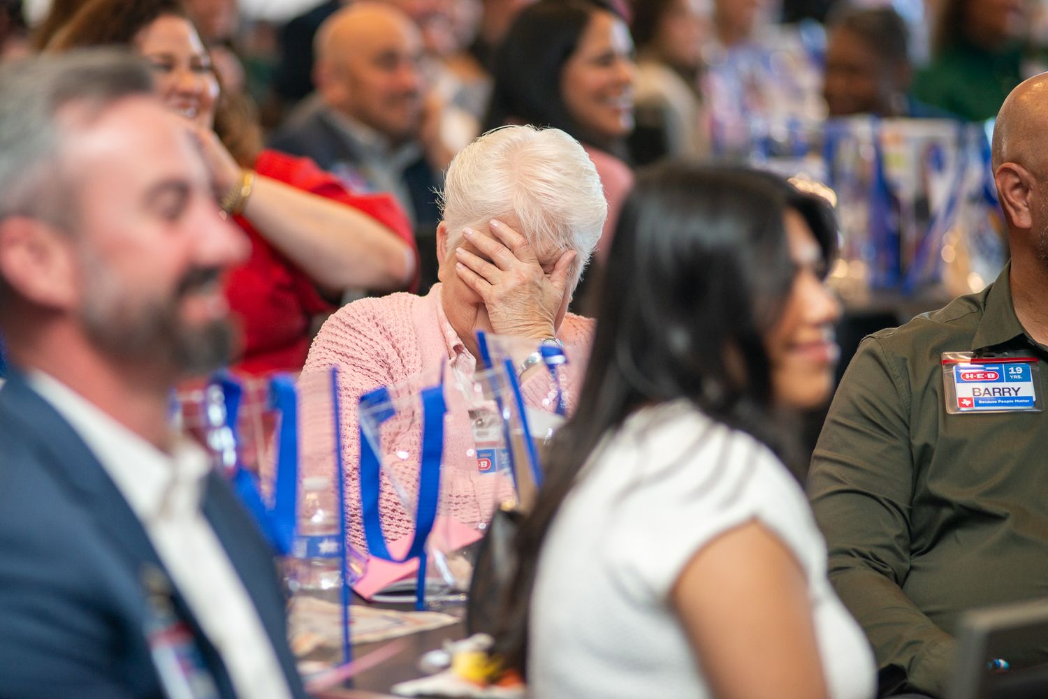 Audience members react with smiles and laughter during an indoor event.