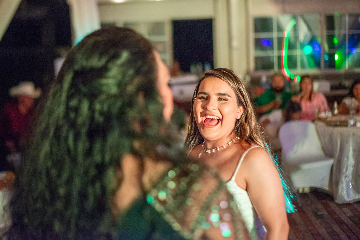 Evening social gathering with festive lighting and attendees enjoying drinks.