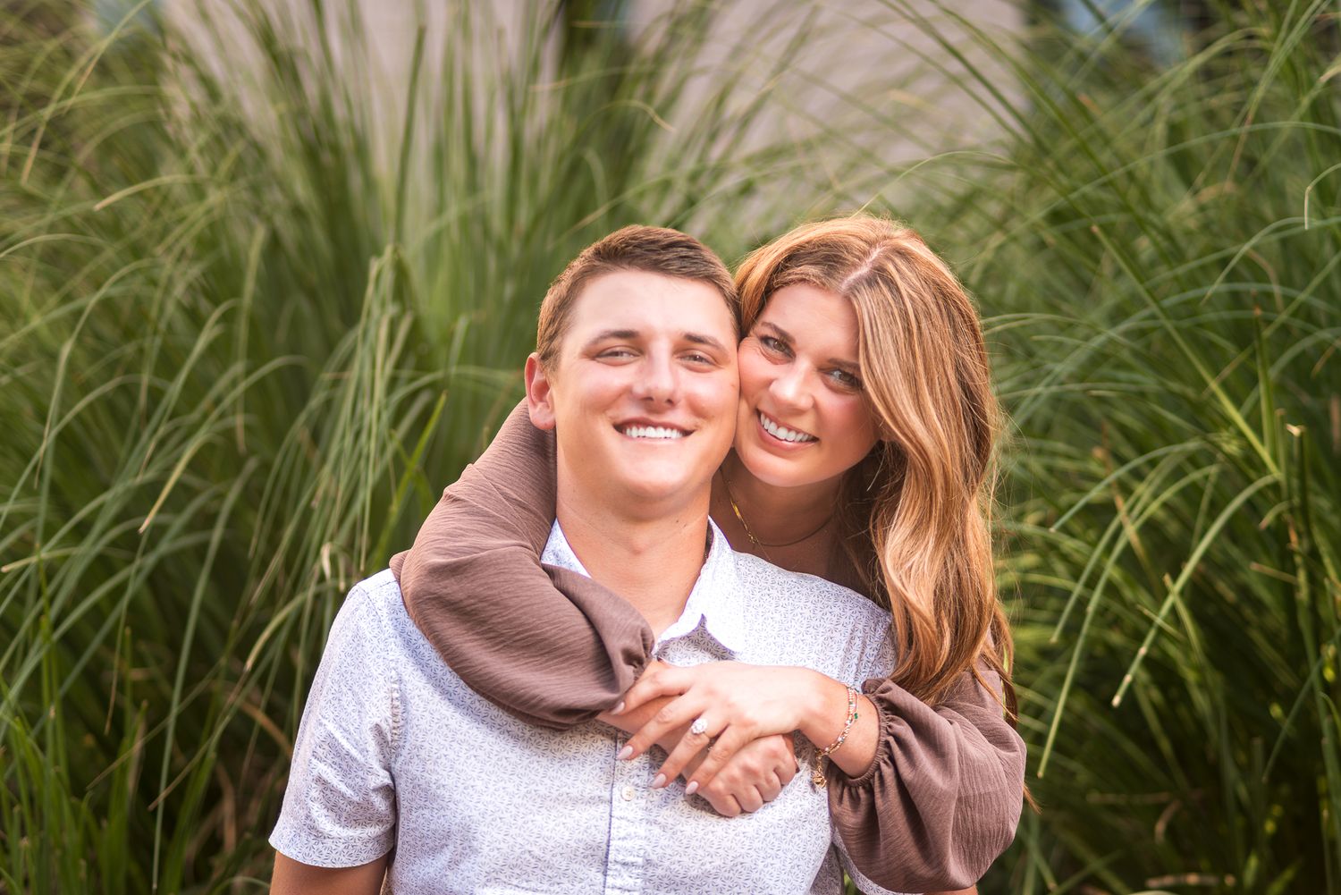 Happy couple poses together in field of tall grass.