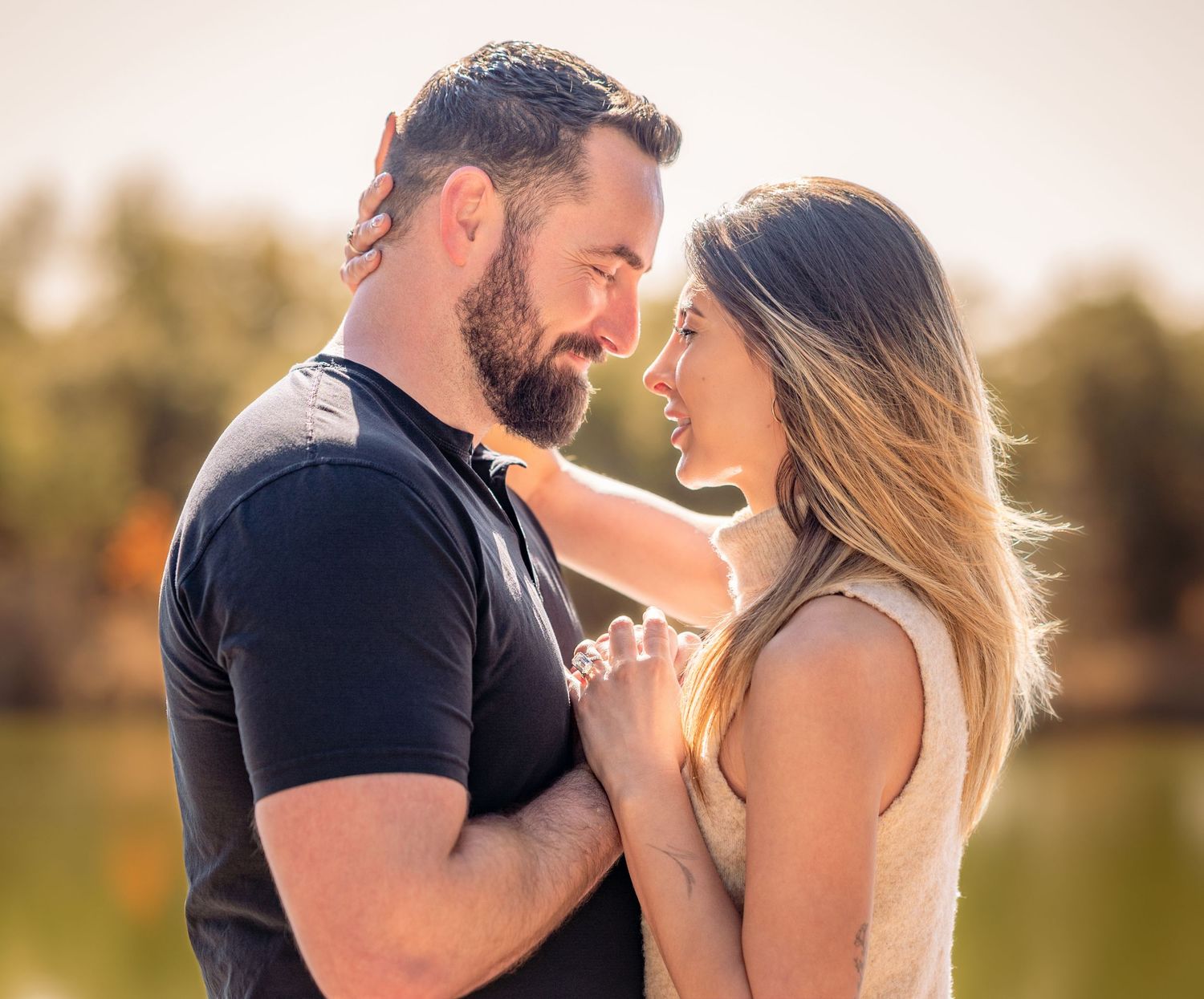 Couple shares intimate moment at sunset in natural outdoor setting.