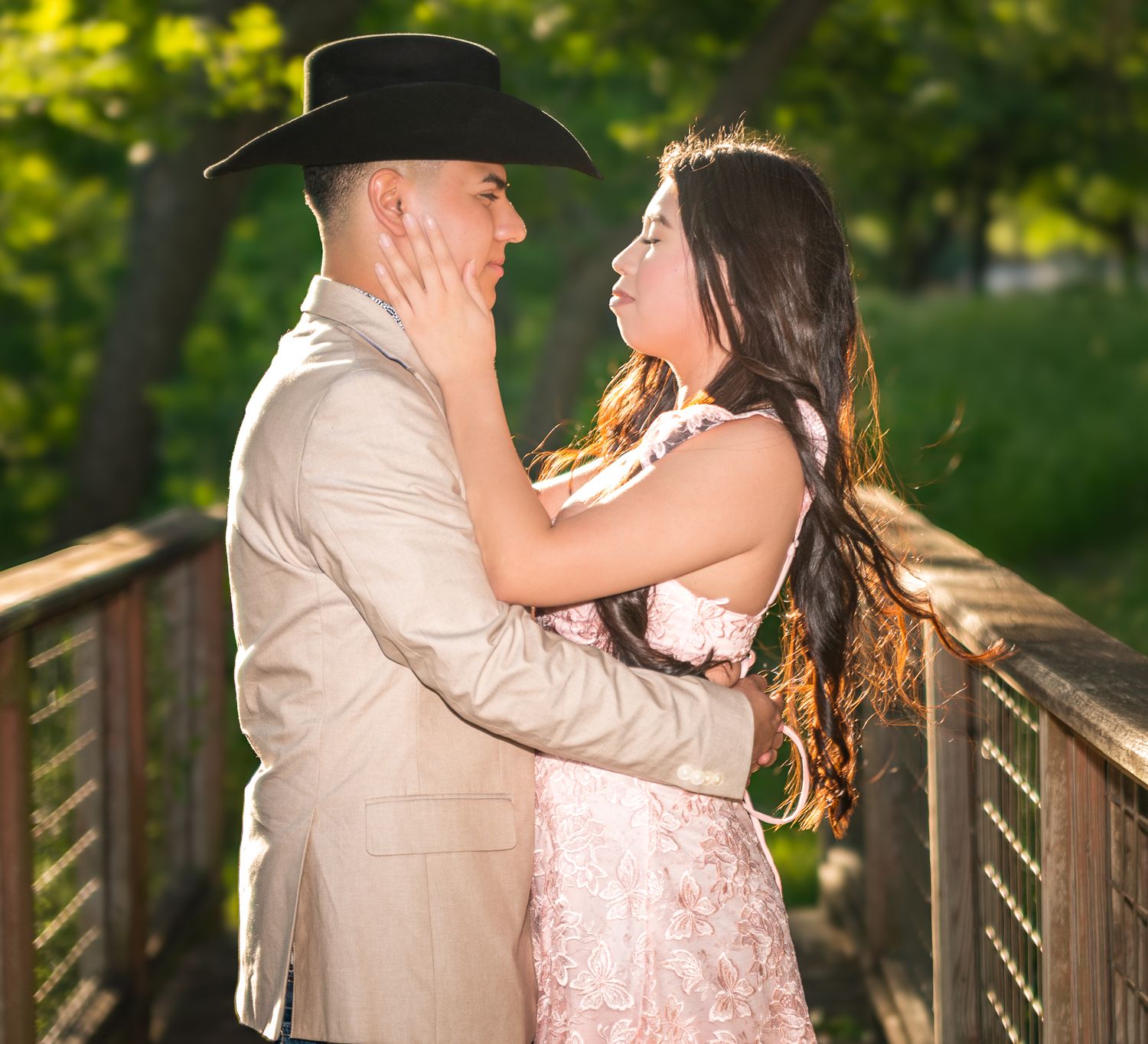 Romantic couple sharing intimate moment on wooden bridge in park setting.