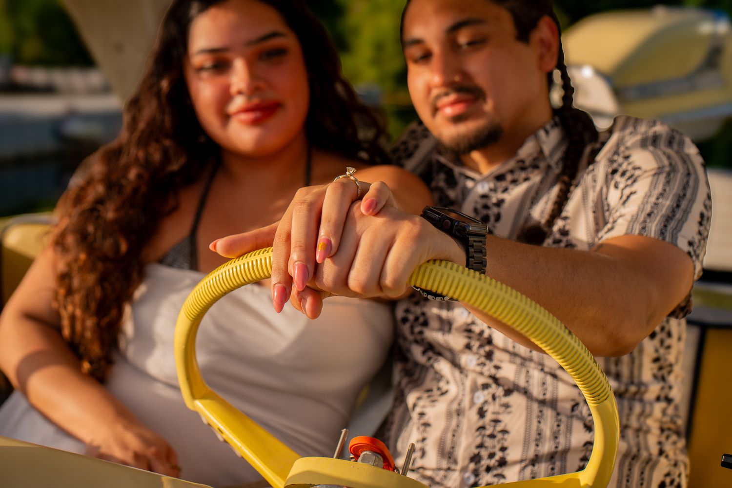 A couple shares a romantic moment while holding a yellow hose in their garden during golden hour lighting.