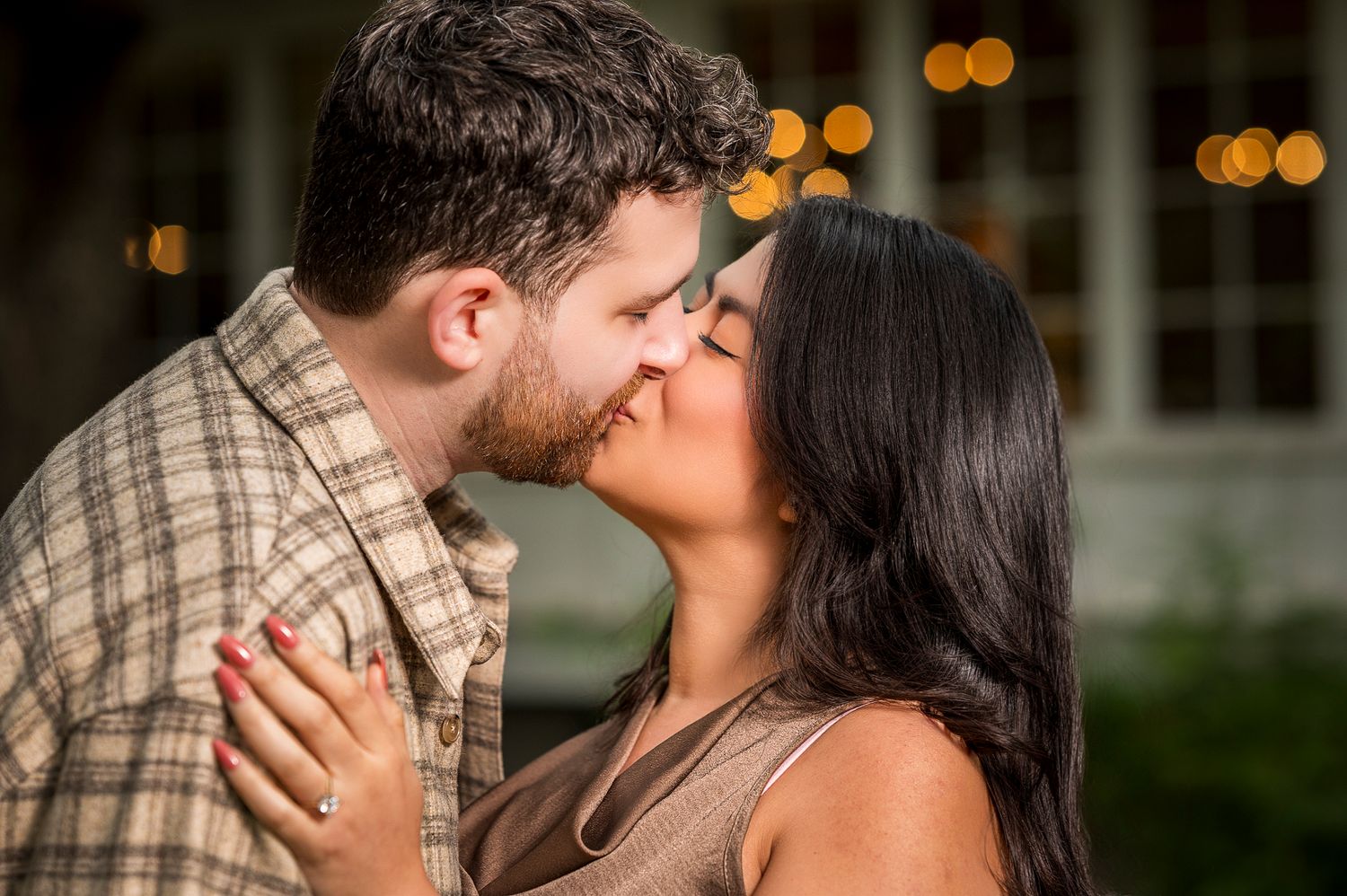 A romantic kiss captured during an engagement photo session with warm lighting.
