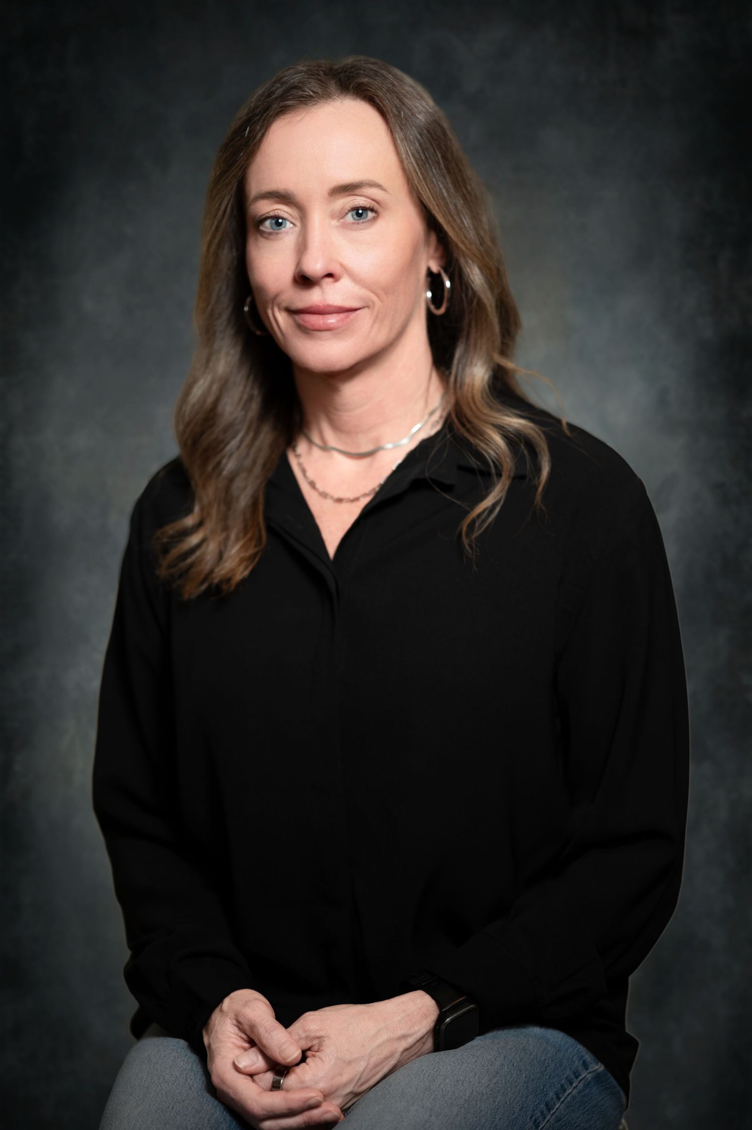 Professional studio portrait series showing someone in a black sweater against a dark dramatic background.