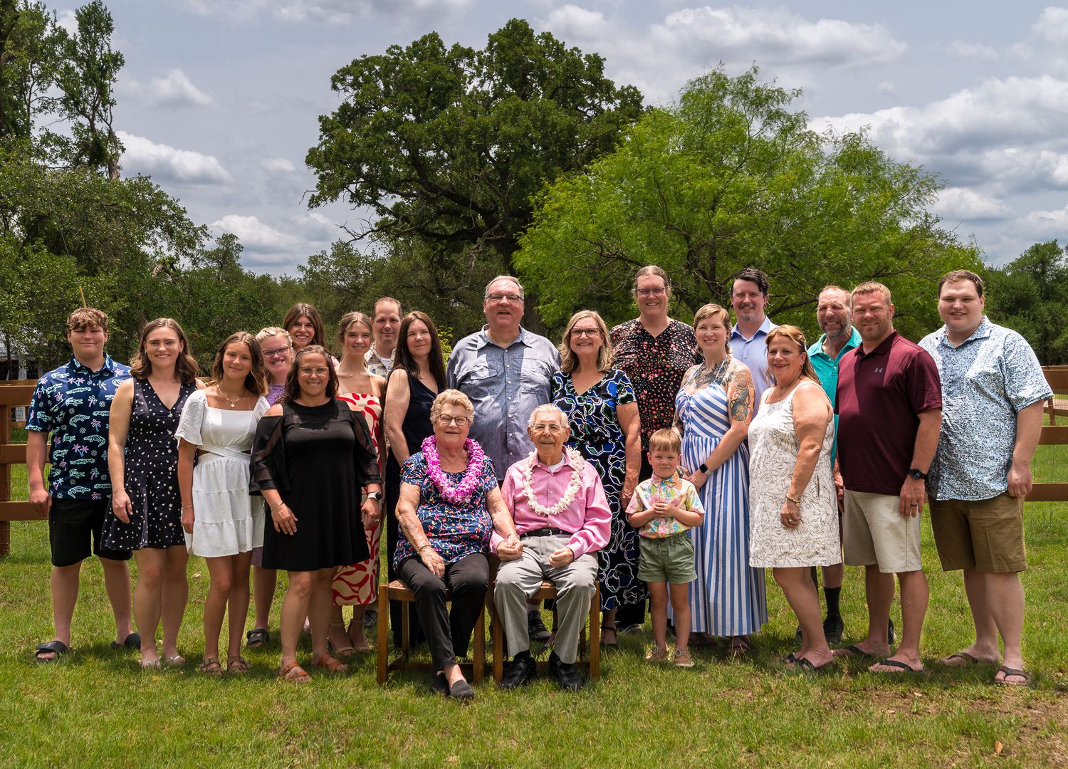 Extended family group photo with multiple generations posed together in grassy field.
