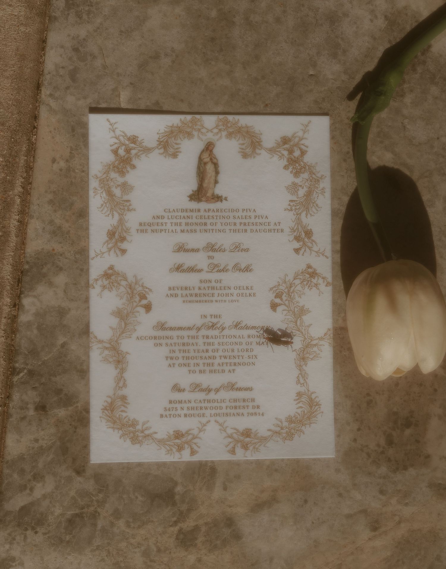 Elegant gold-bordered wedding invitation with Virgin Mary and white tulip.