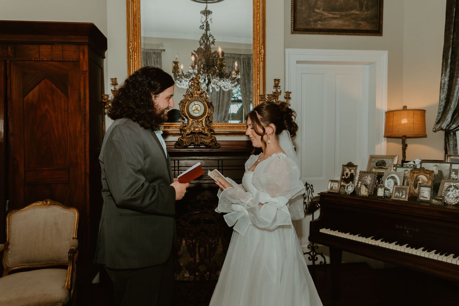 Bride and groom exchange vows indoors beside a grand piano in elegant vintage room.