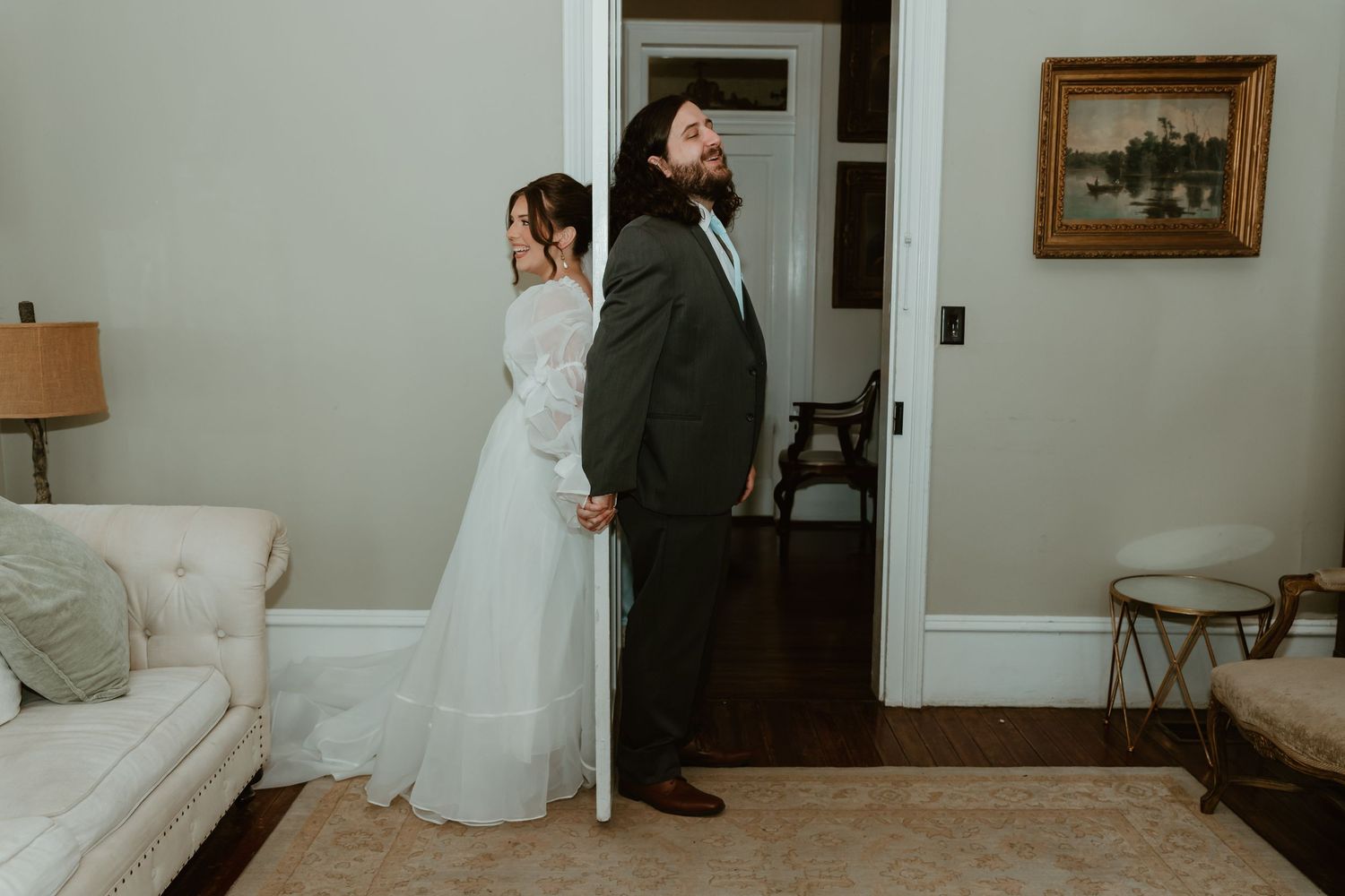 Bride and groom sharing a sweet first touch moment through a doorway before the wedding ceremony.