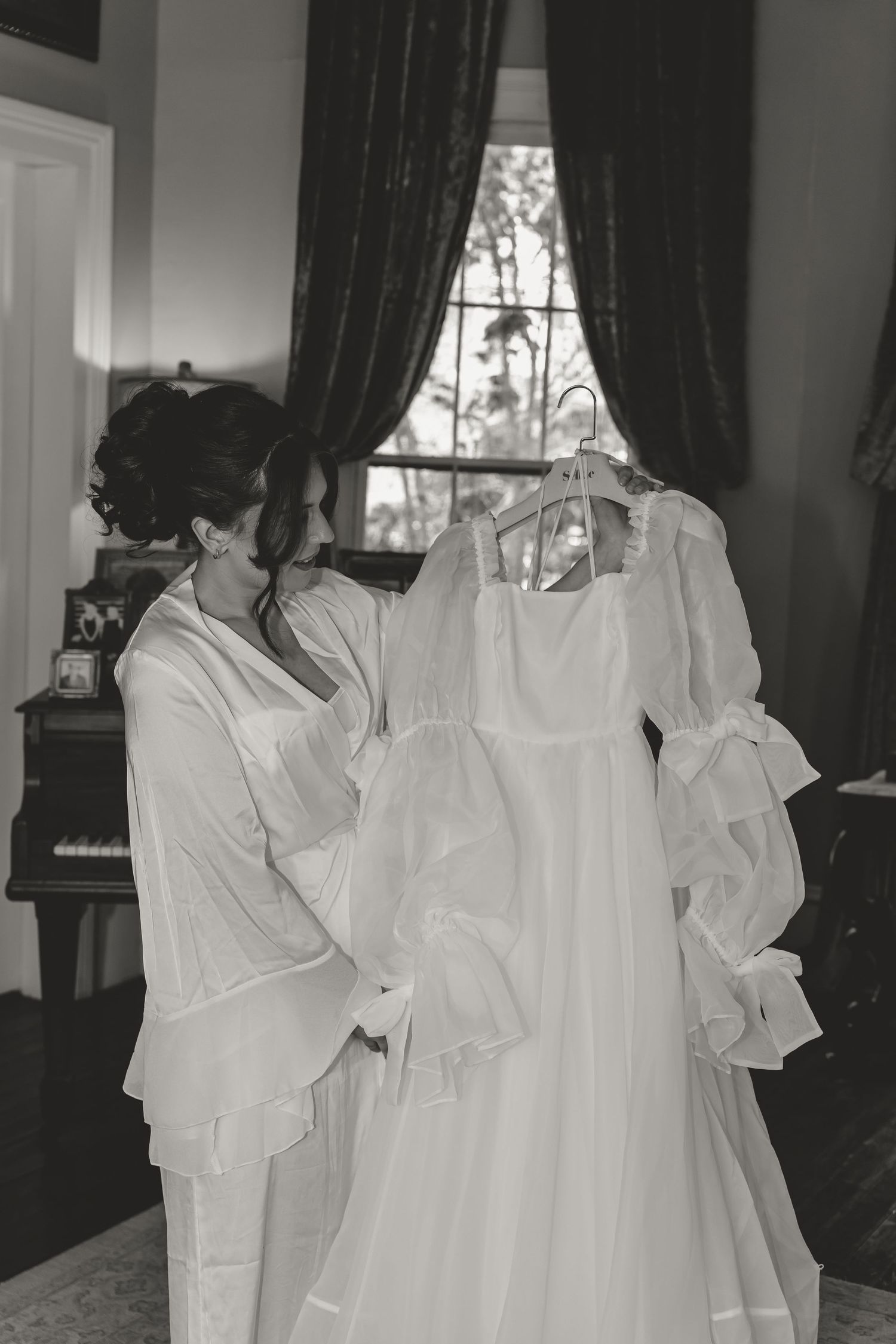 Black and white photo of bride examining her flowing wedding dress before the ceremony.