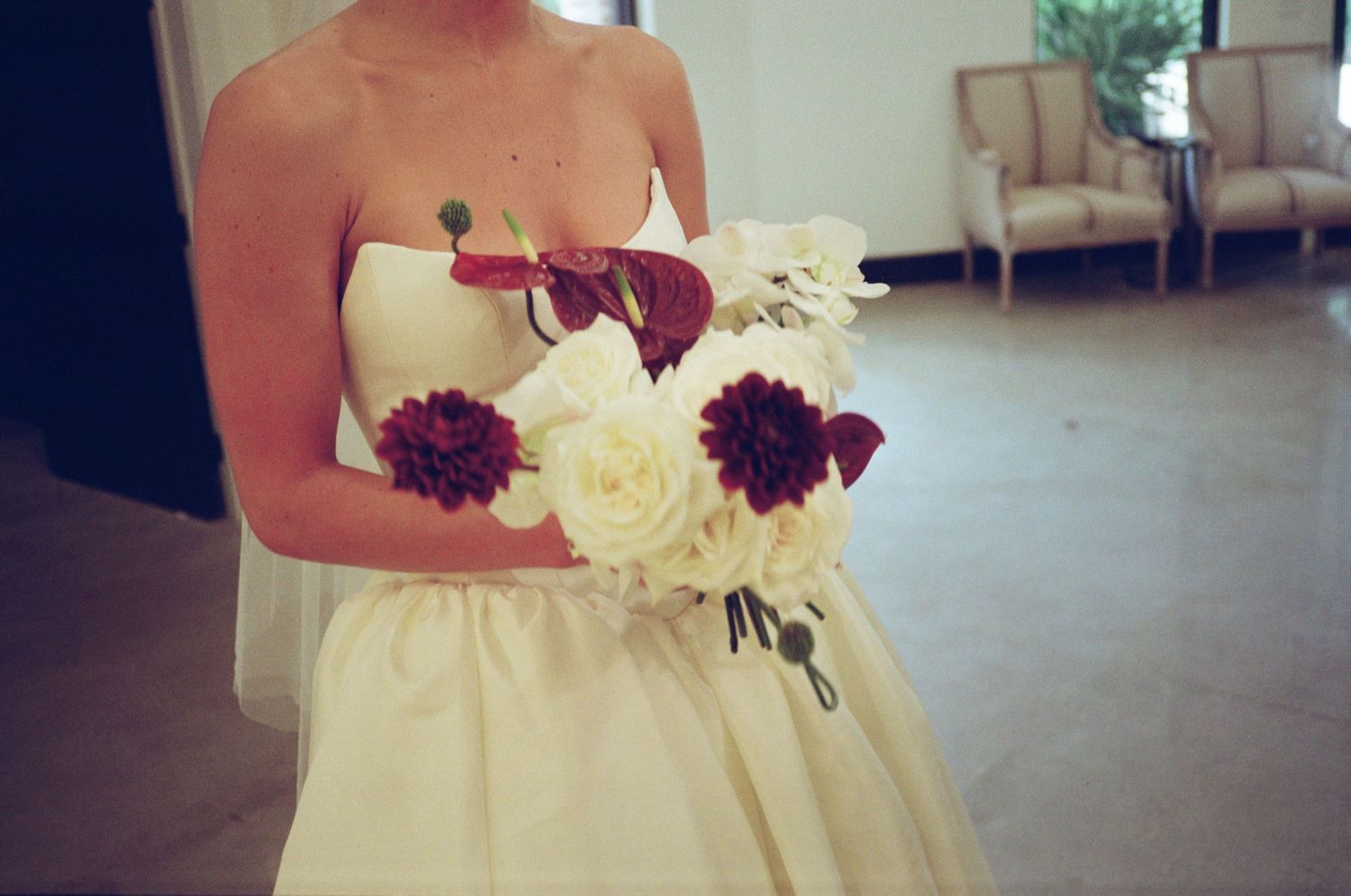 Wedding dress detail with burgundy and white flowers attached to bodice.