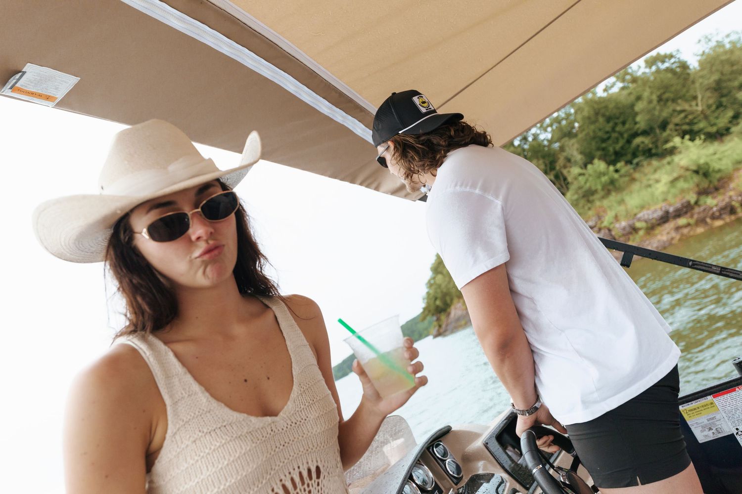 People enjoying a sunny day on a boat while sipping drinks and wearing sunglasses and hats.