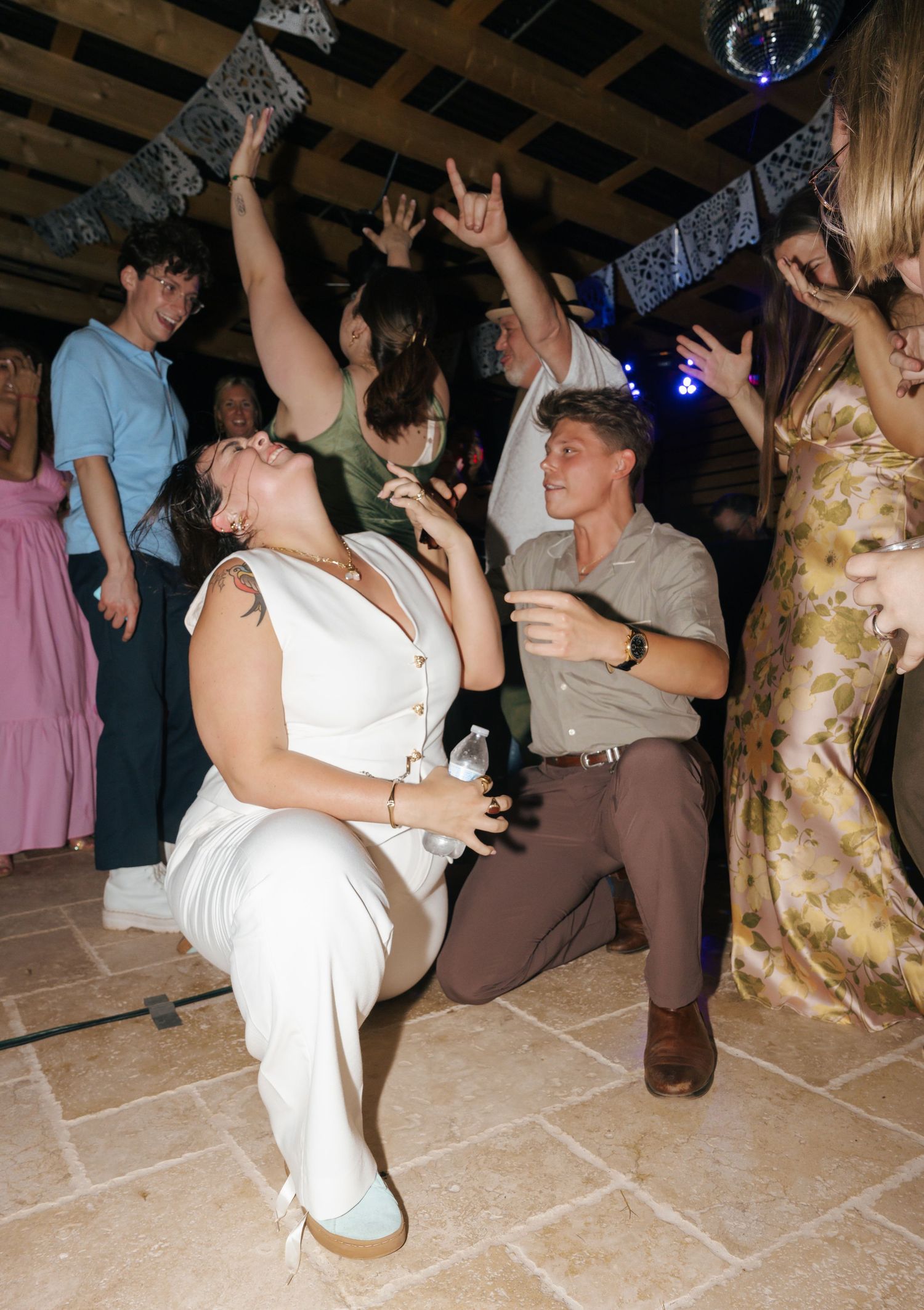 People dancing and celebrating at a lively party on a tiled floor.