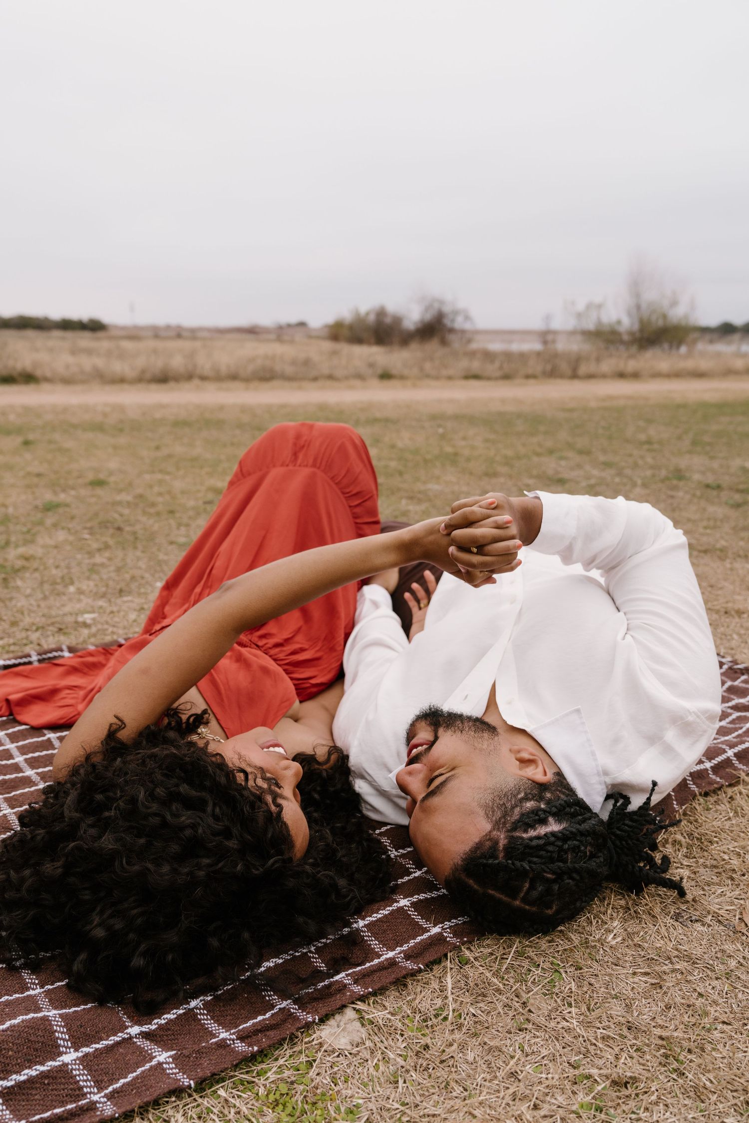 A sequence of four photos showing someone resting peacefully on a plaid blanket in an outdoor field setting.