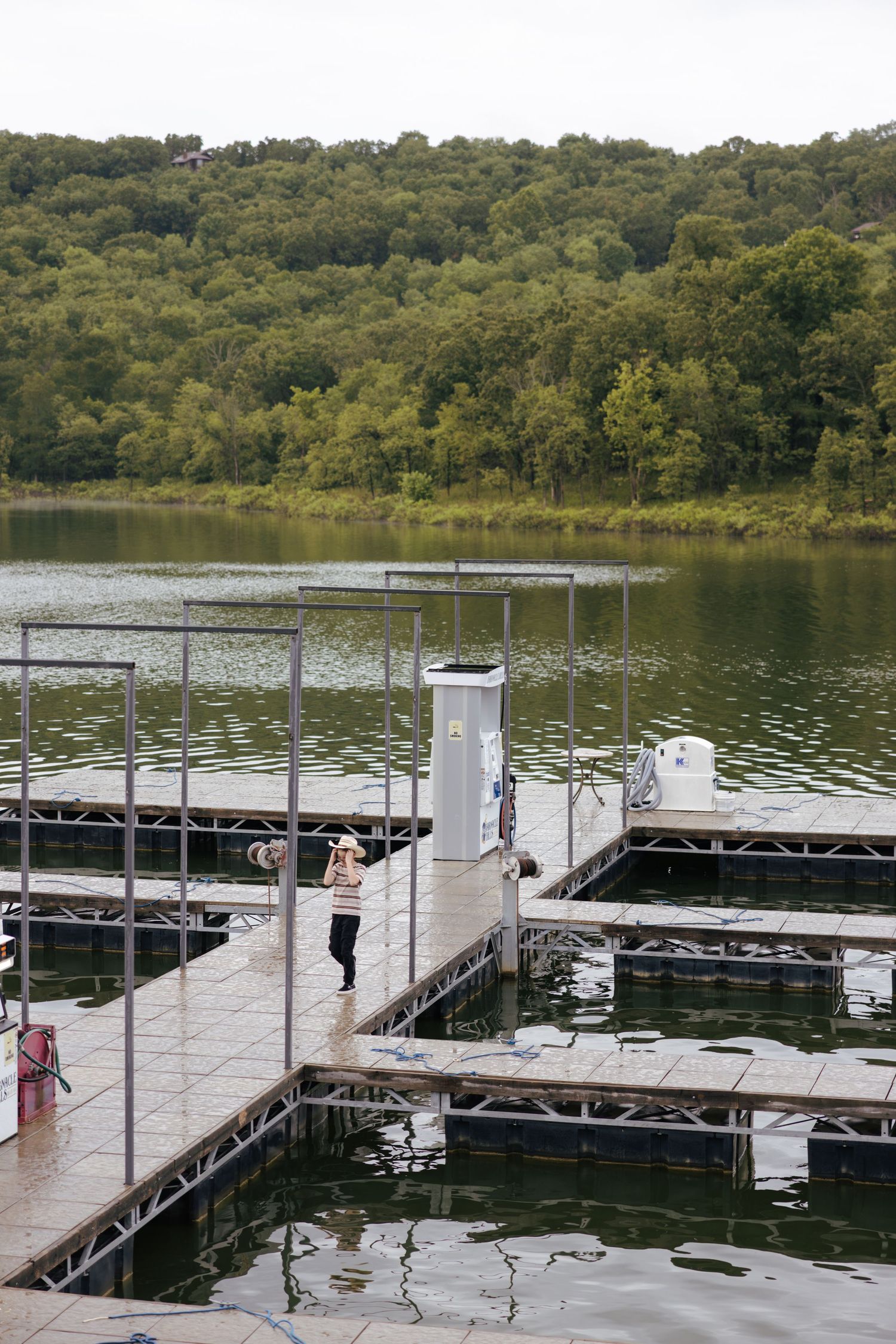 A scenic lake dock with multiple boat slips surrounded by lush green forest on a calm summer day.