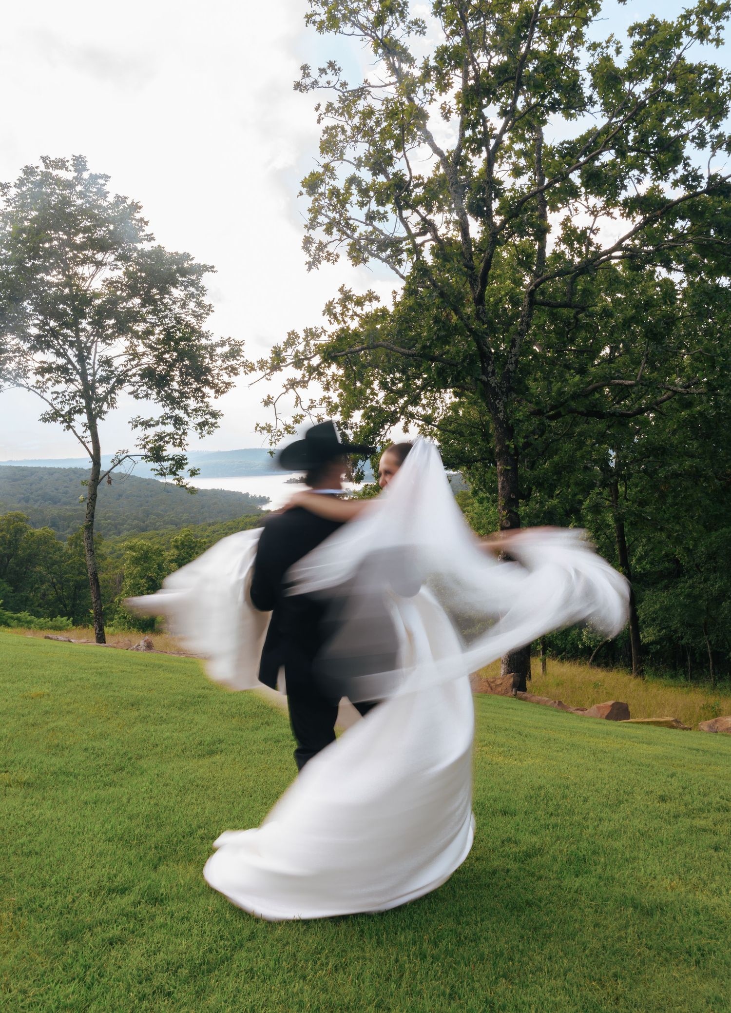 Artistic motion blur captures a twirling wedding dress against a natural landscape.