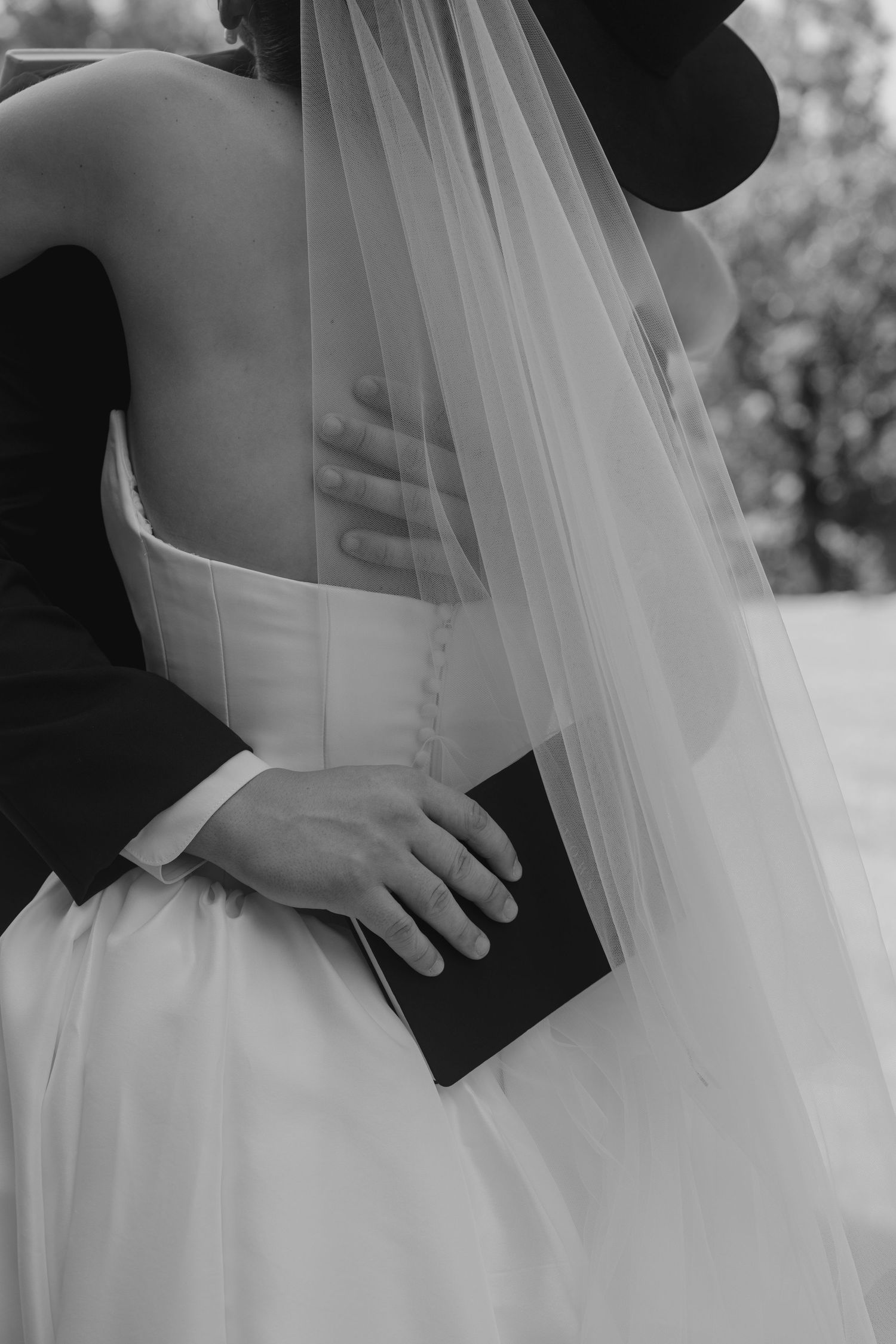 Close-up details of a bride's white wedding dress and flowing veil.