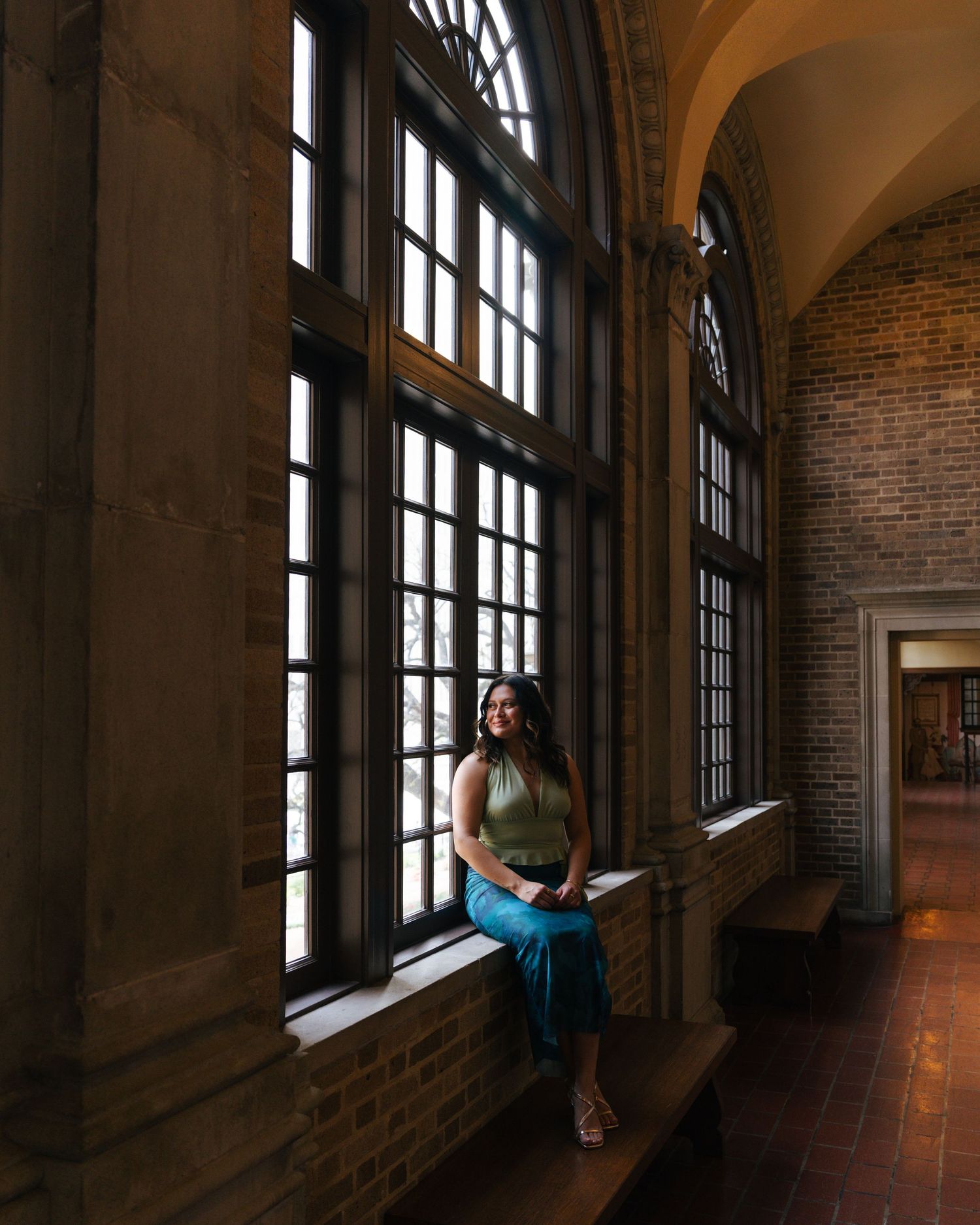 A sequence of five photos showing someone reading by a window in a long hallway with brick walls and arched ceilings.
