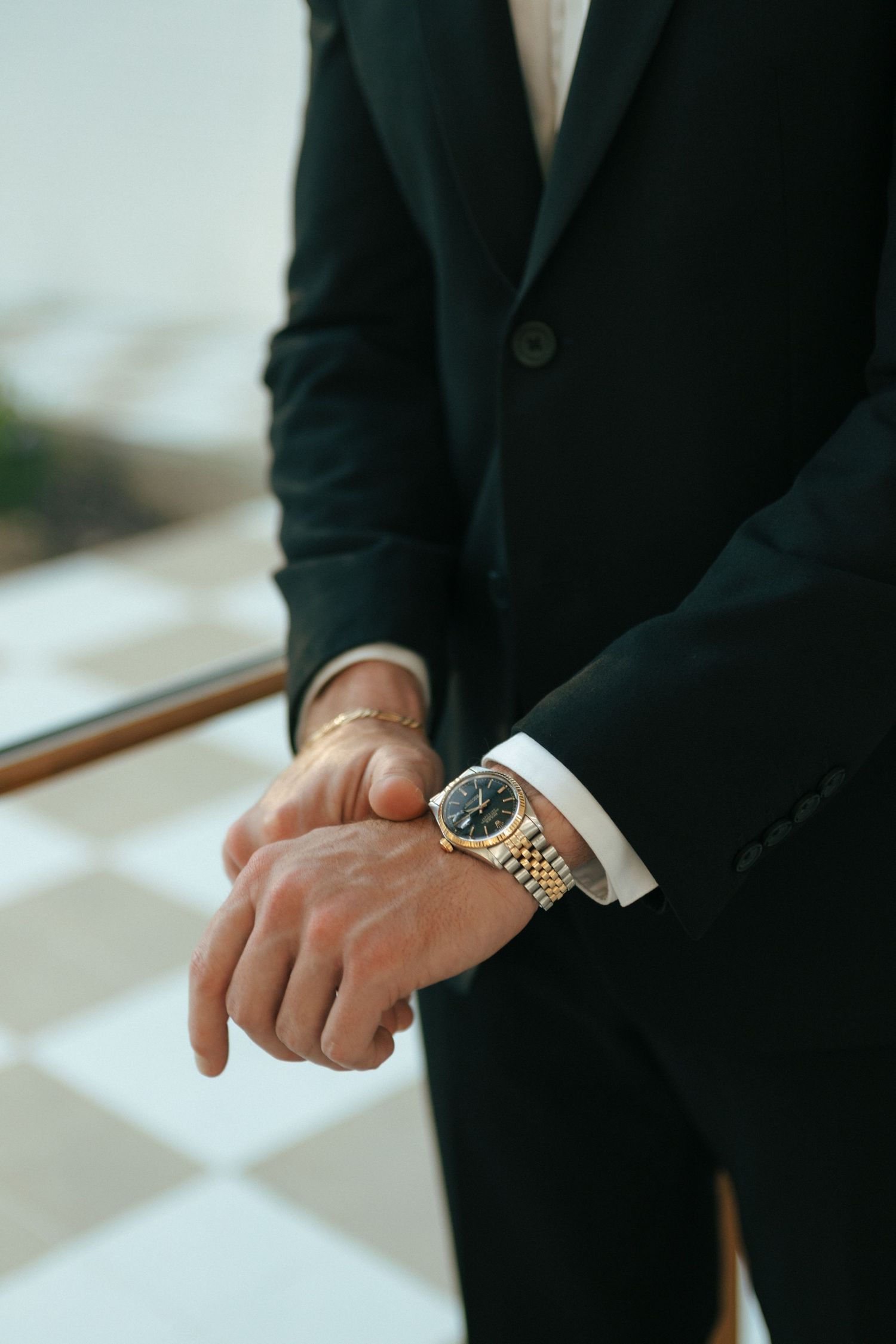 Close-up of hands wearing formal suit and wristwatch.