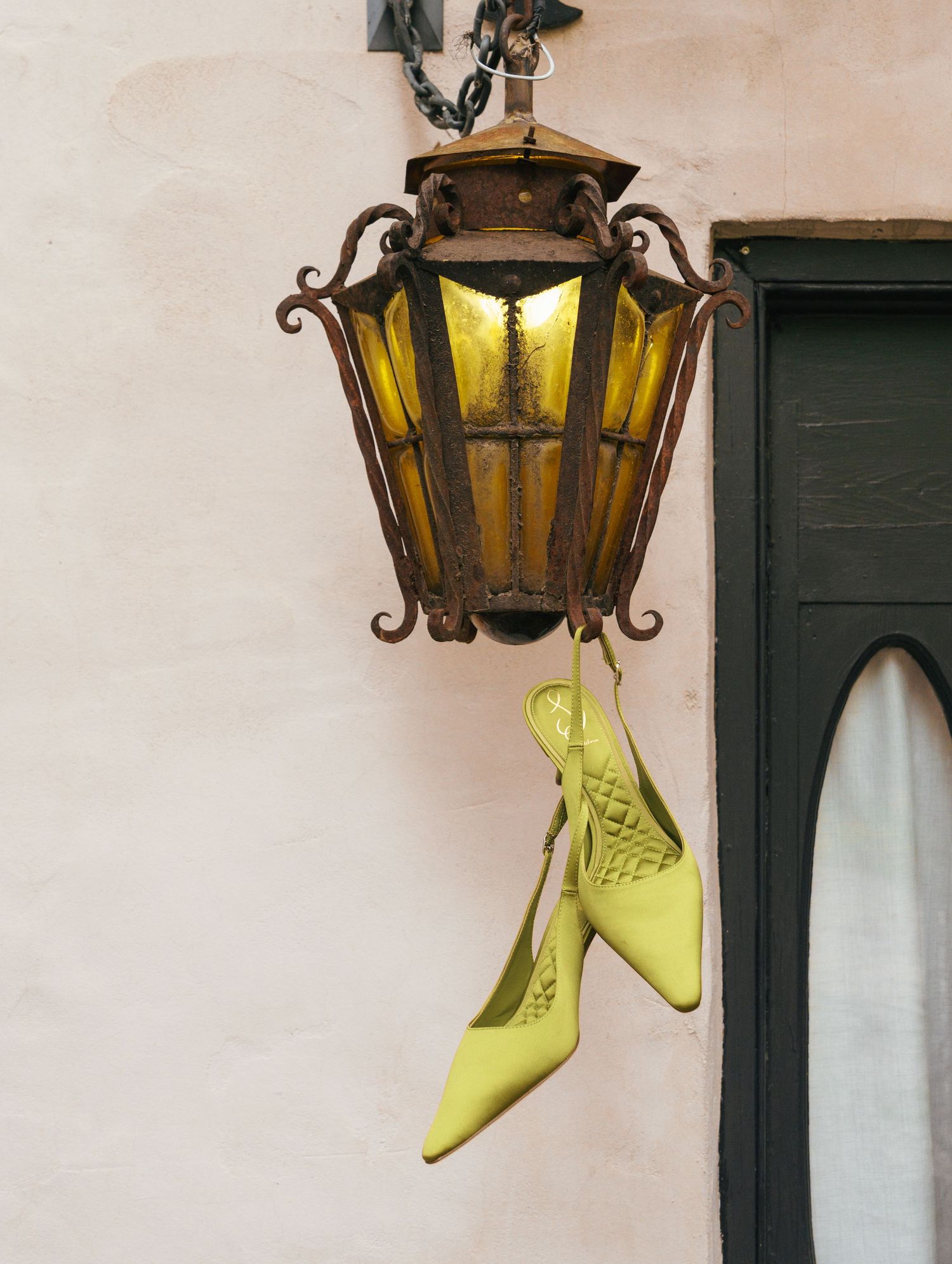 Yellow shoes peek out from behind vintage lanterns mounted on a white wall.