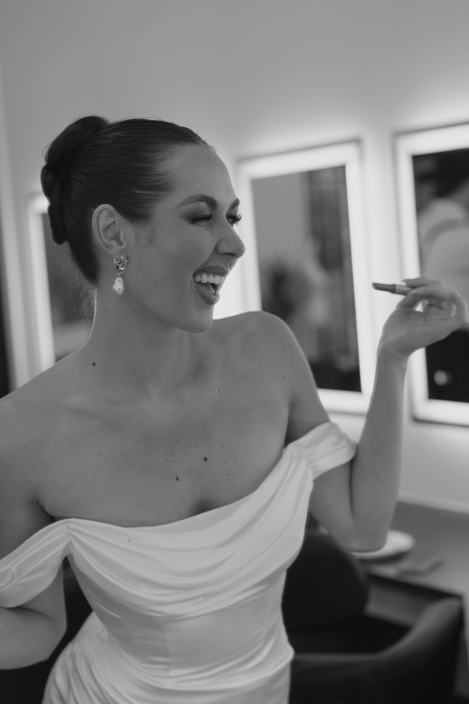 Elegant one-shoulder white wedding dress detail shown in black and white photography.