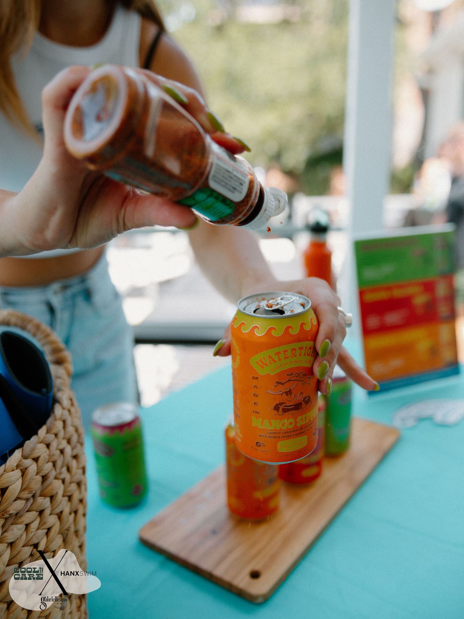 Colorful canned beverages being served on wooden boards against a turquoise background.