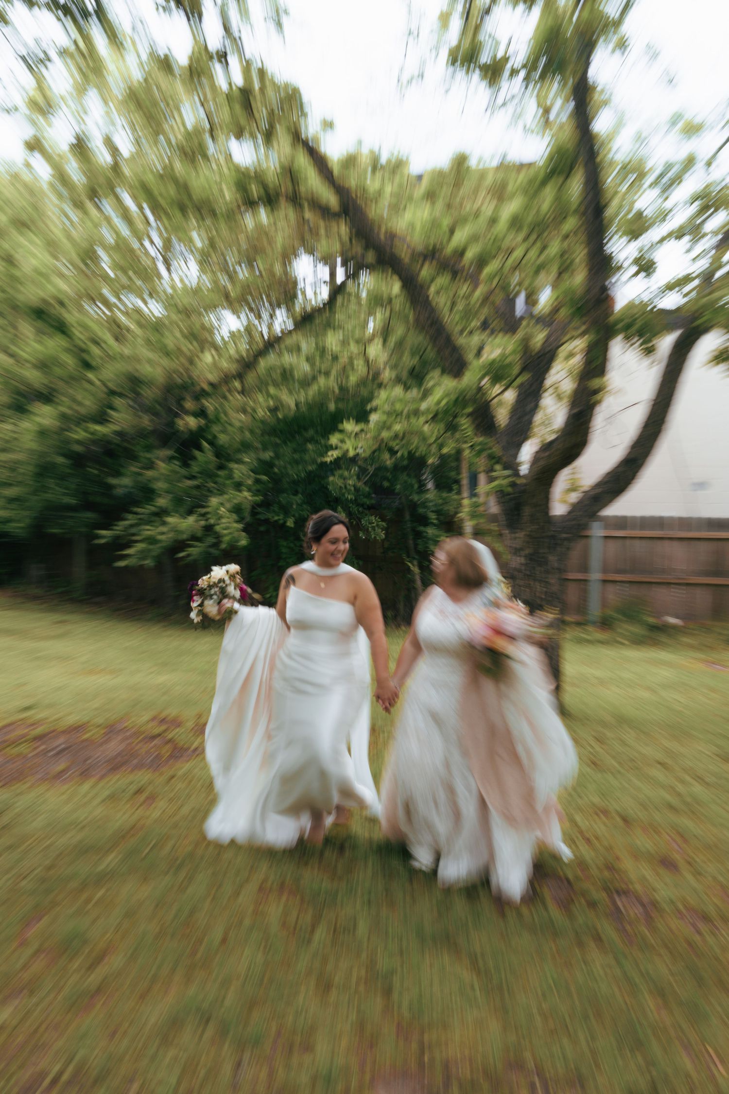 Motion blur captures a group of people in flowing white dresses running together through a grassy lawn.