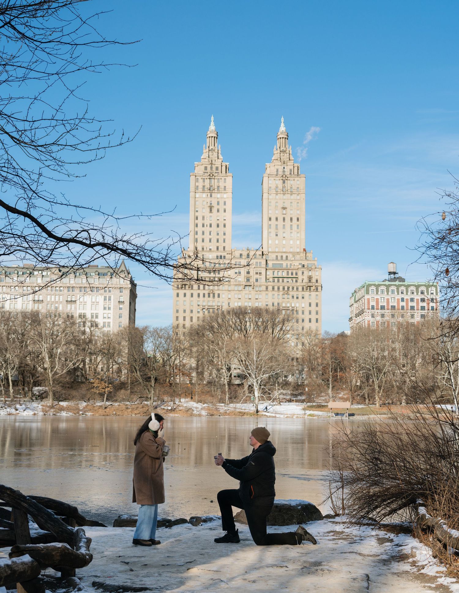 A panoramic sequence of people proposing in front of the El Dorado building along Central Park's frozen lake in winter.