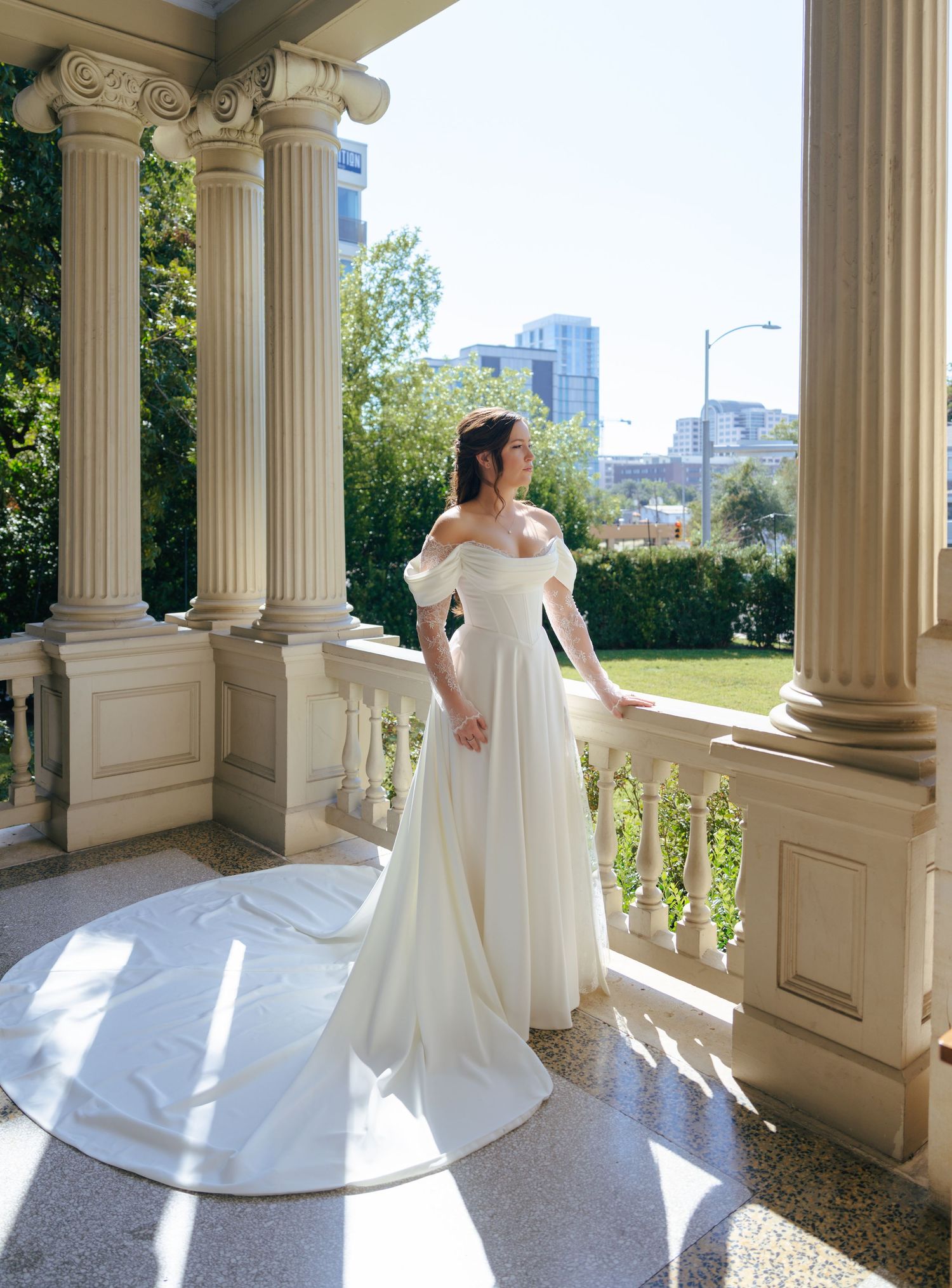 White wedding dress photographed against classical columns and architecture in natural light.