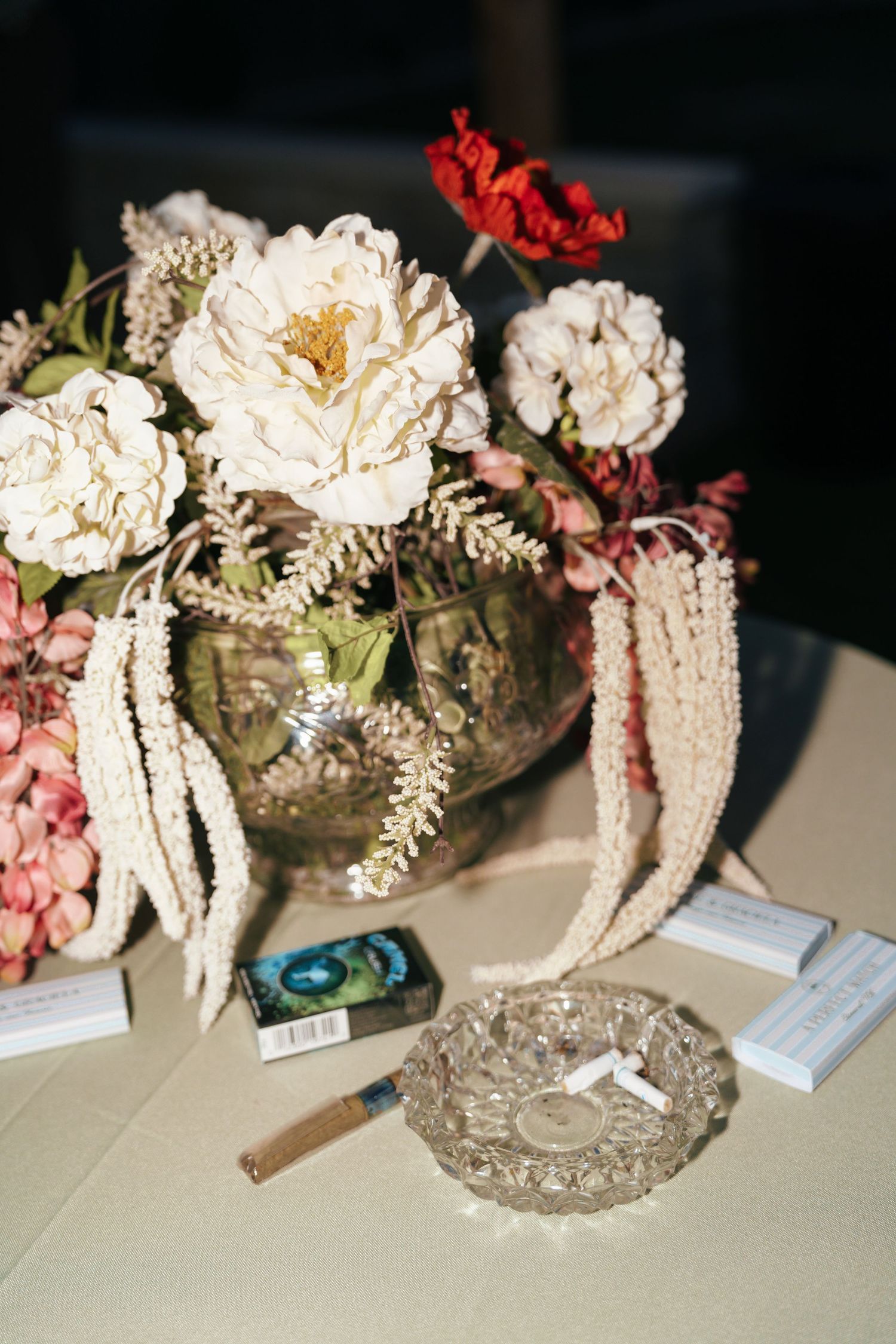Elegant floral centerpieces with white cascading flowers and greenery arranged in vintage silver vases on a light surface.