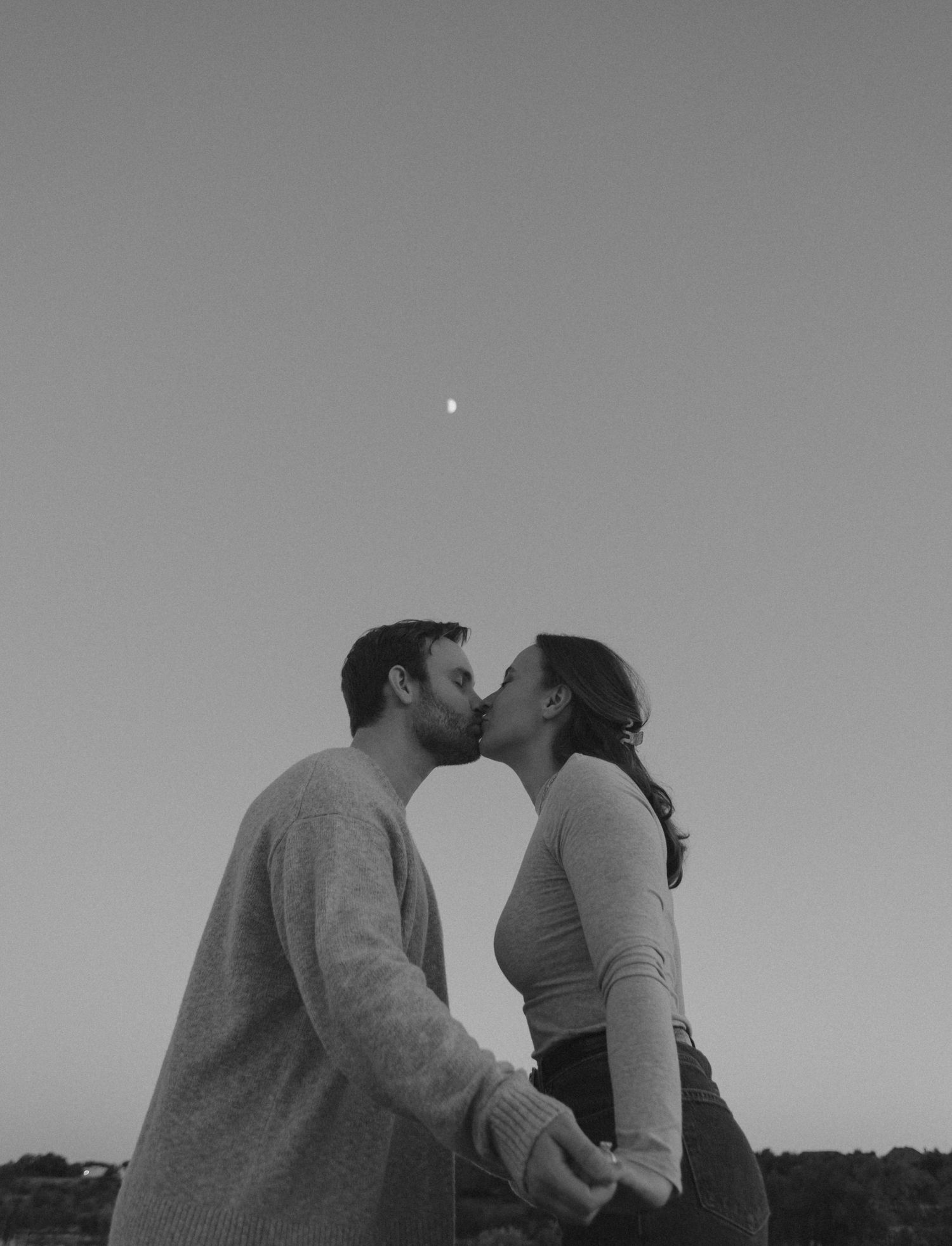 Silhouetted couple shares intimate moment under twilight sky.