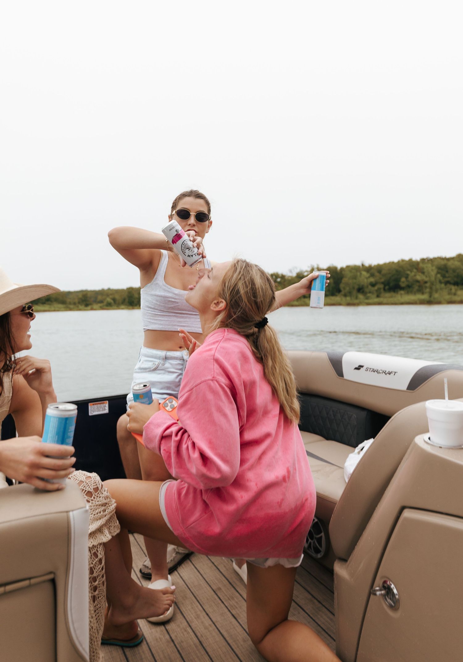 People enjoying drinks and relaxing on a pontoon boat deck on a sunny summer day at the lake.
