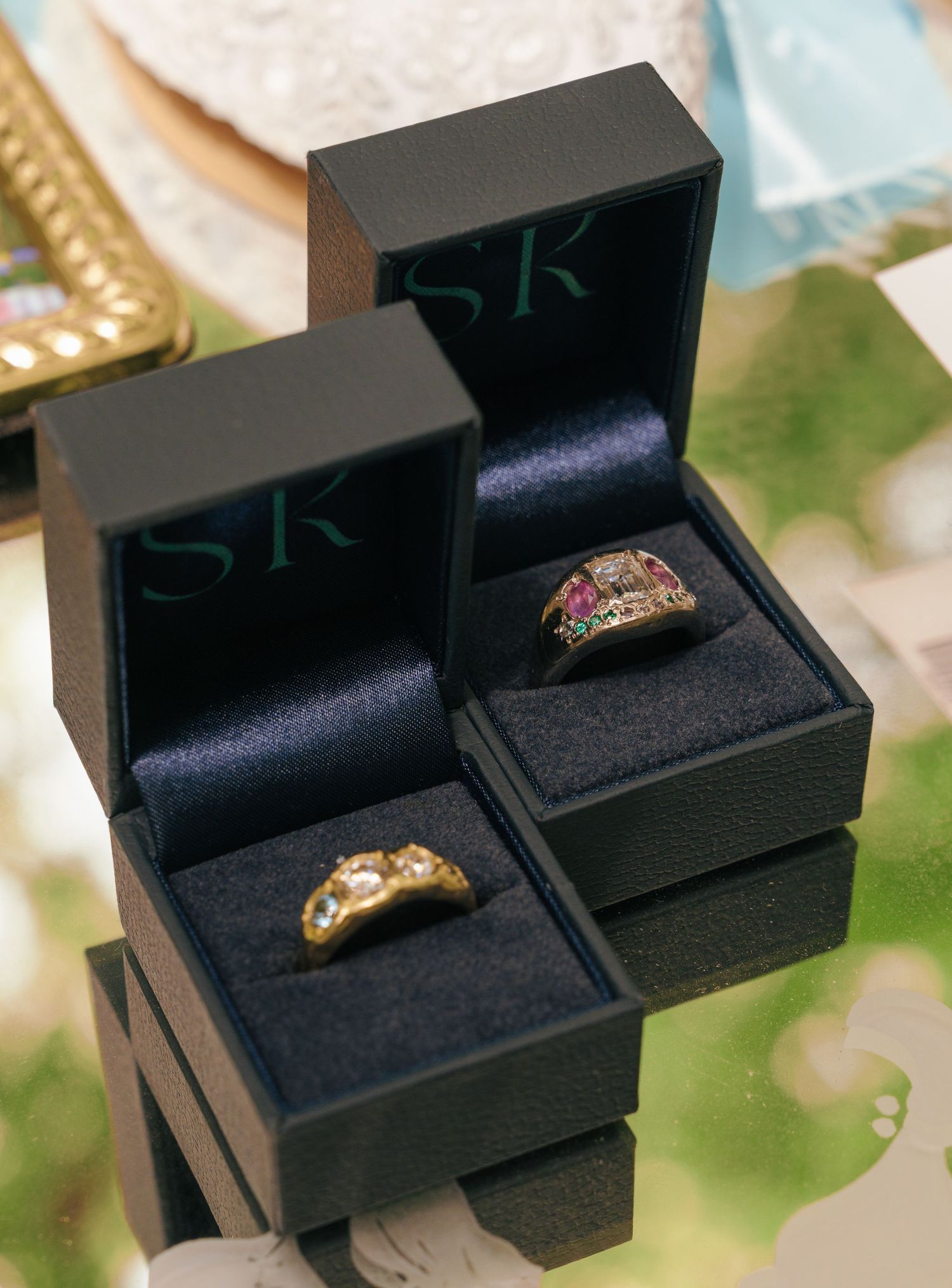 Multiple views of a black jewelry box displaying a sparkling ring with a gemstone against a navy velvet interior.