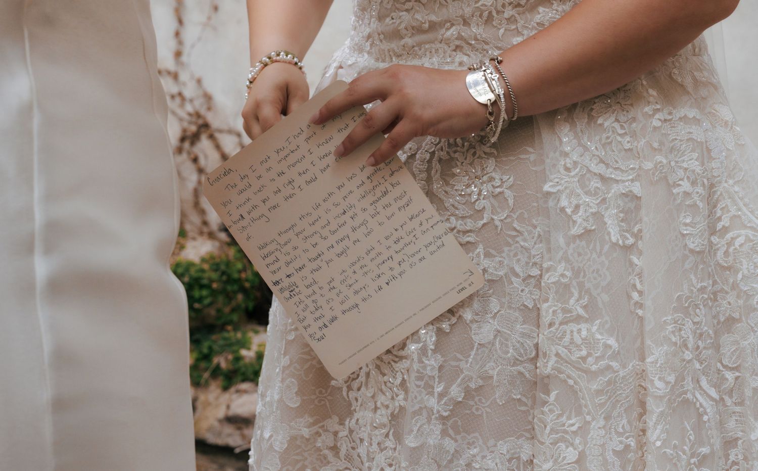Close-up details of an ornate white lace wedding dress with delicate beading and embroidery patterns.