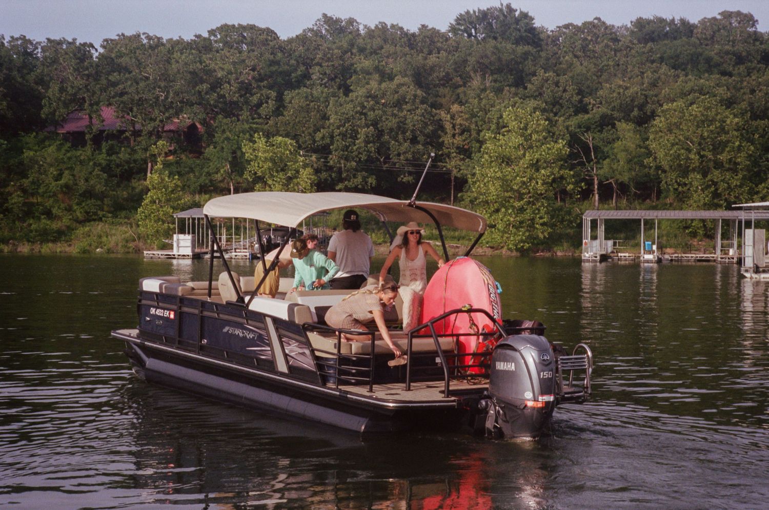 A series of pontoon boats cruising along a scenic lake surrounded by lush green trees on a sunny day.