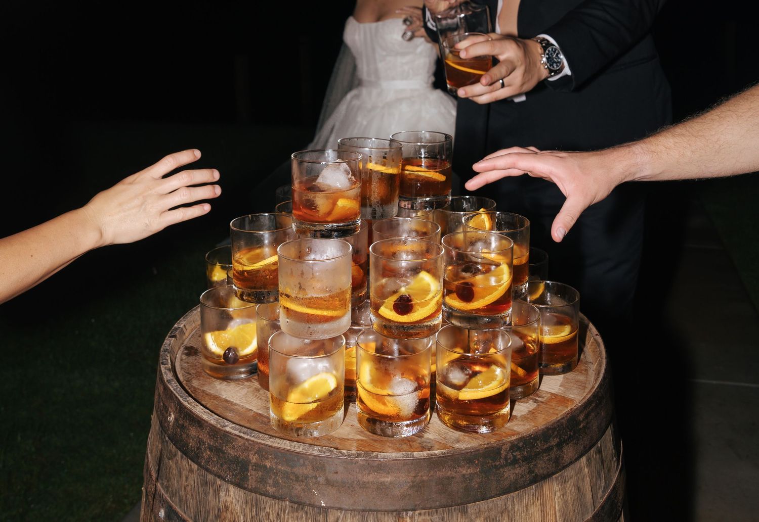 Cocktails with orange garnishes arranged on a wooden barrel display.
