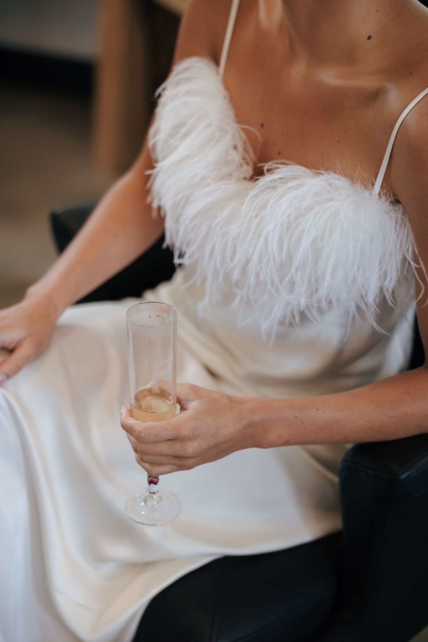 Close-up details of a white feather-trimmed wedding dress.