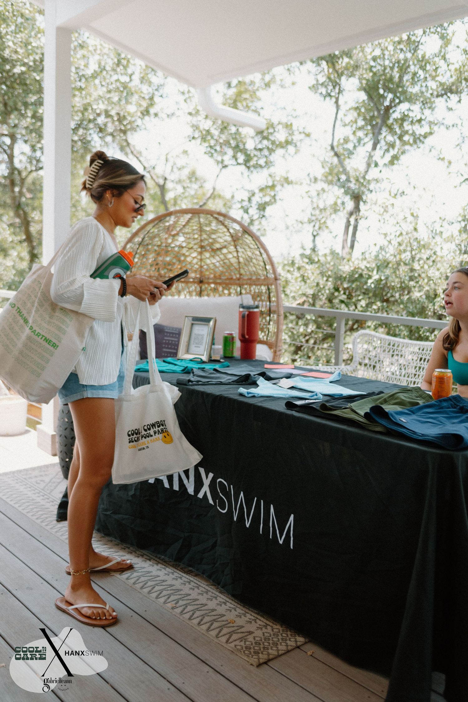 Display table with black tablecloths and merchandise set up at an outdoor event.
