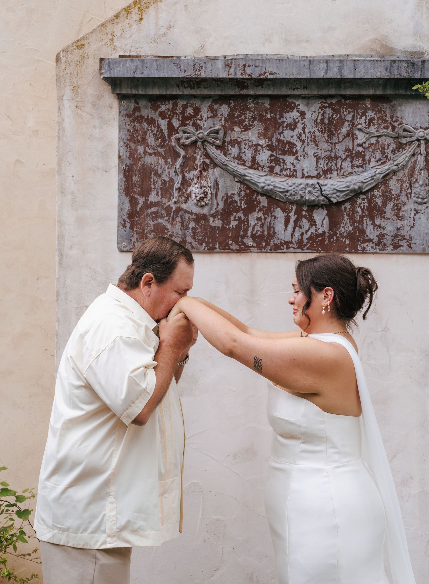 A playful sequence of wedding photos showing a couple in white attire interacting through a rustic wall opening.